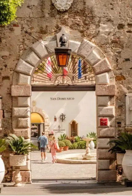 Decorative circular stained‑glass window set in a stone façade in Taormina