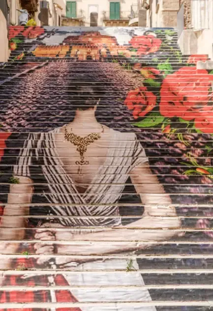 Artistic staircase in Noto with large mural depicting a woman in a white dress, a popular viewpoint 