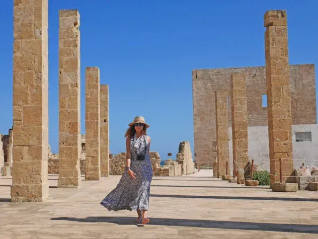 Traveler exploring ancient ruins in the Vendicari Nature Reserve under a clear blue sky