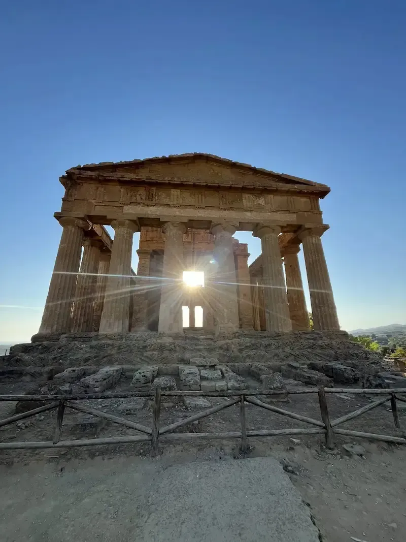 Greek temple in Agrigento at sunset with warm sky and surrounding landscape
