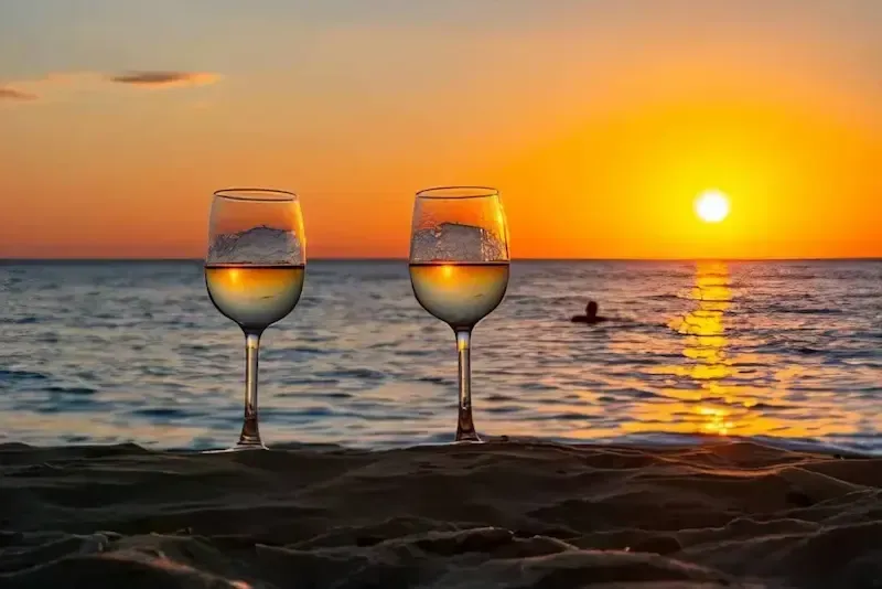 Wine glasses on a Sicilian beach at sunset with ocean view