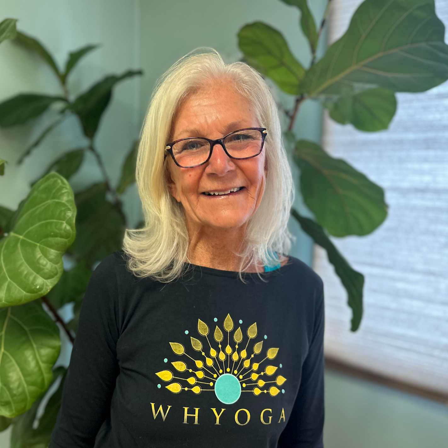 A woman wearing glasses and a black shirt that says why yoga