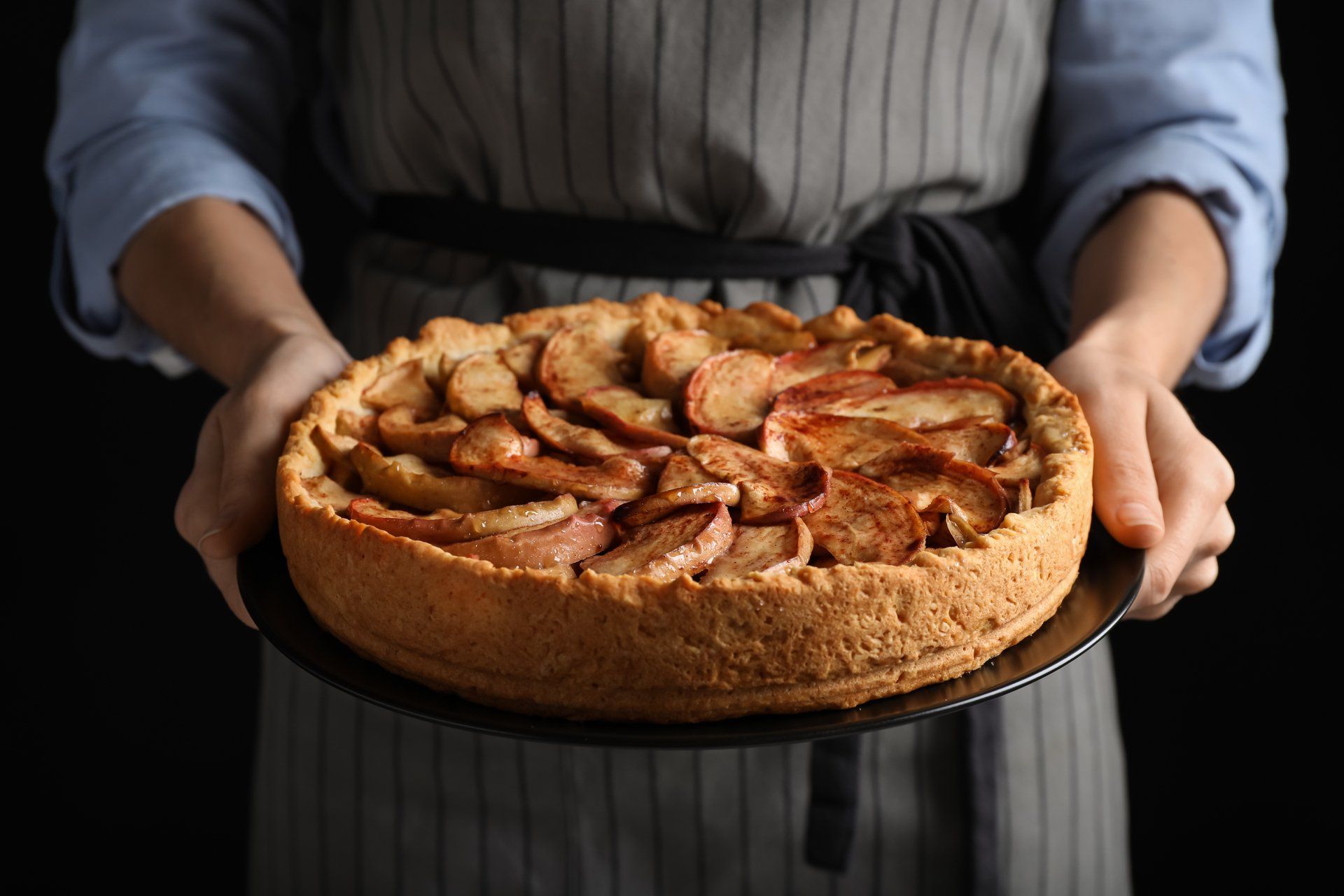 woman holding bowl with apple pies, closeup