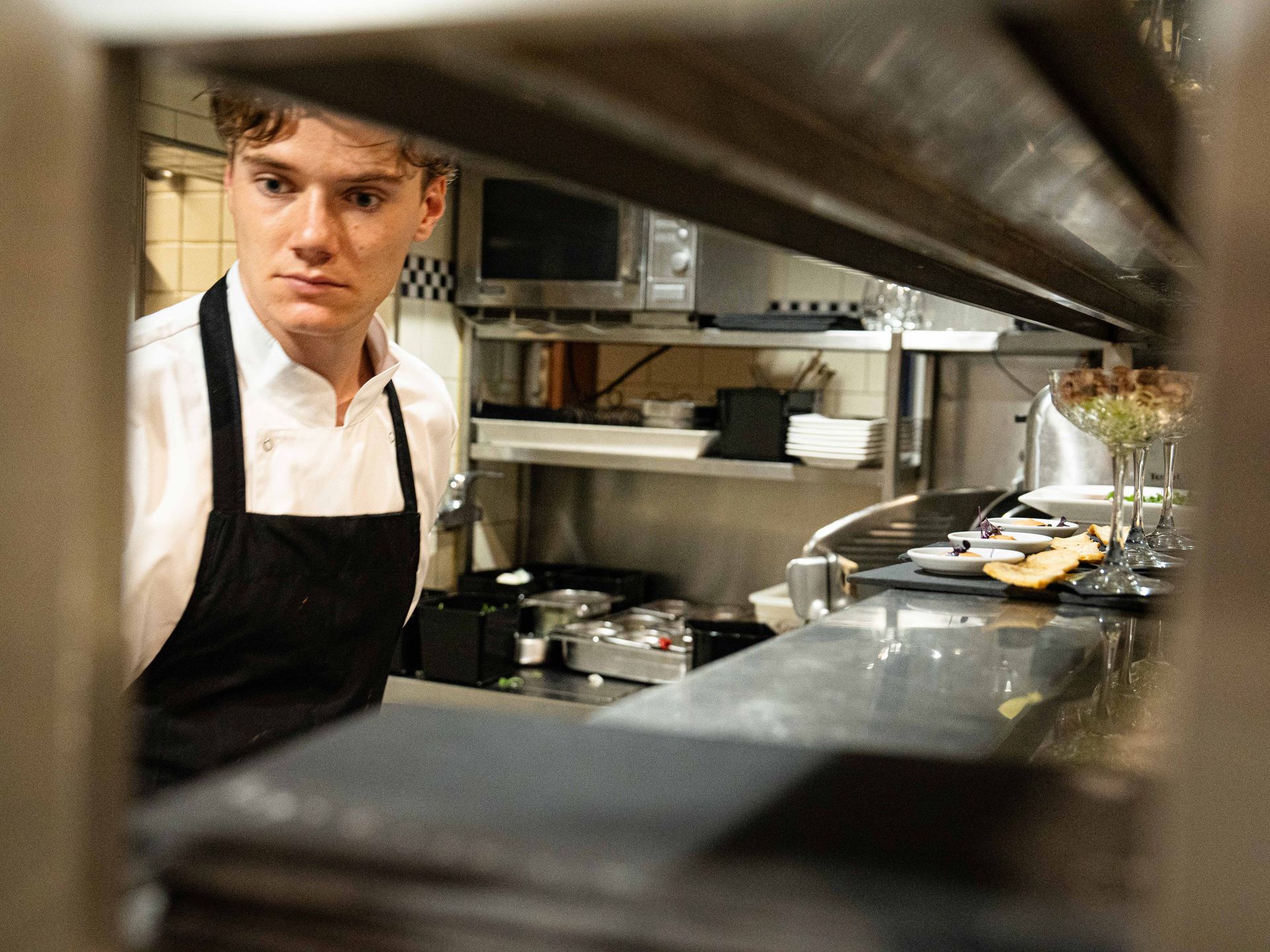 Een man met een schort staat in een keuken