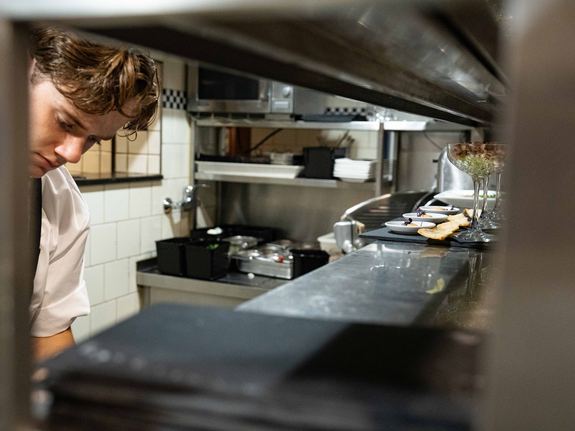 Een man kijkt door een raam naar een keuken