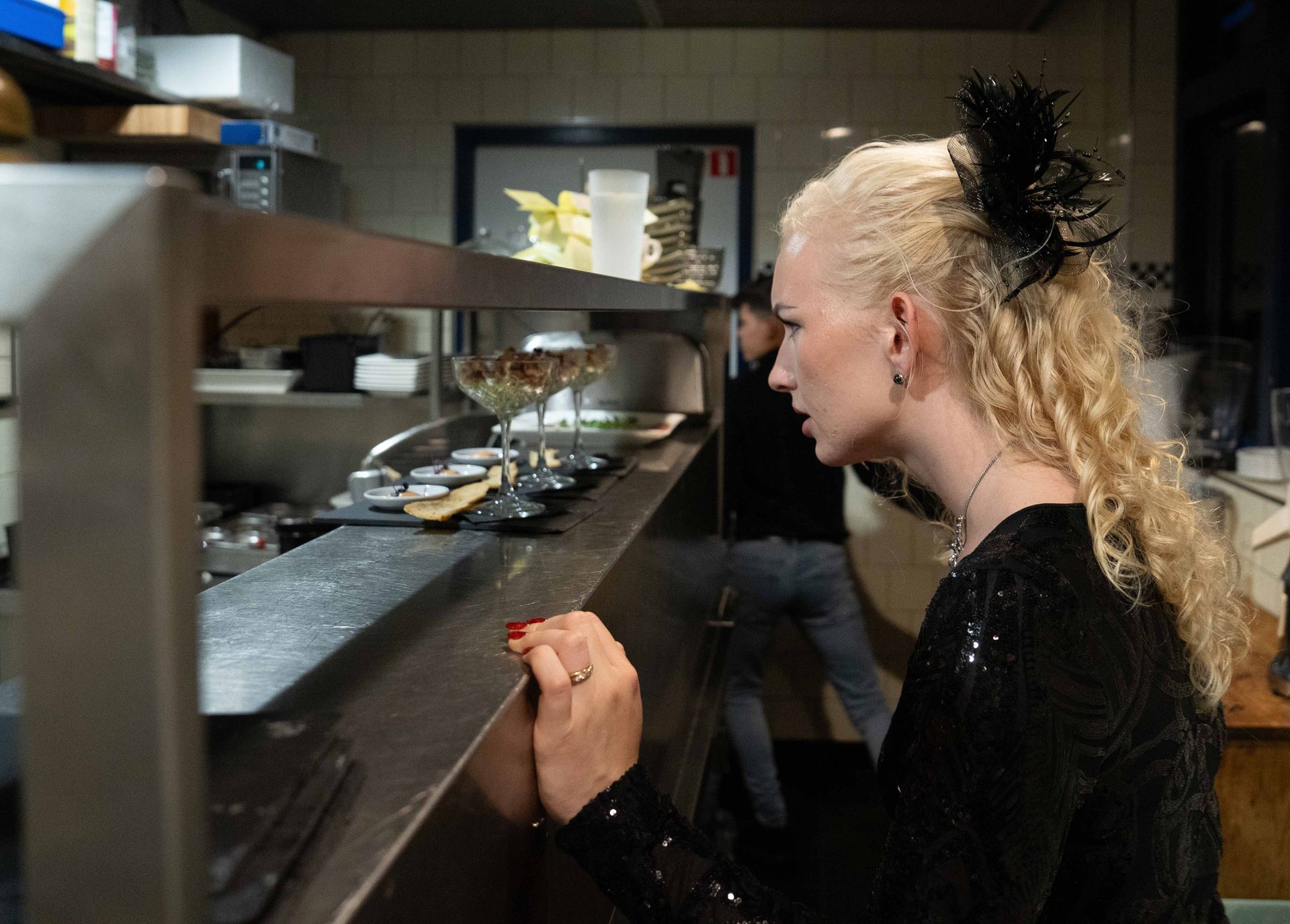 Een vrouw in een zwarte jurk staat aan een toonbank in een restaurant.