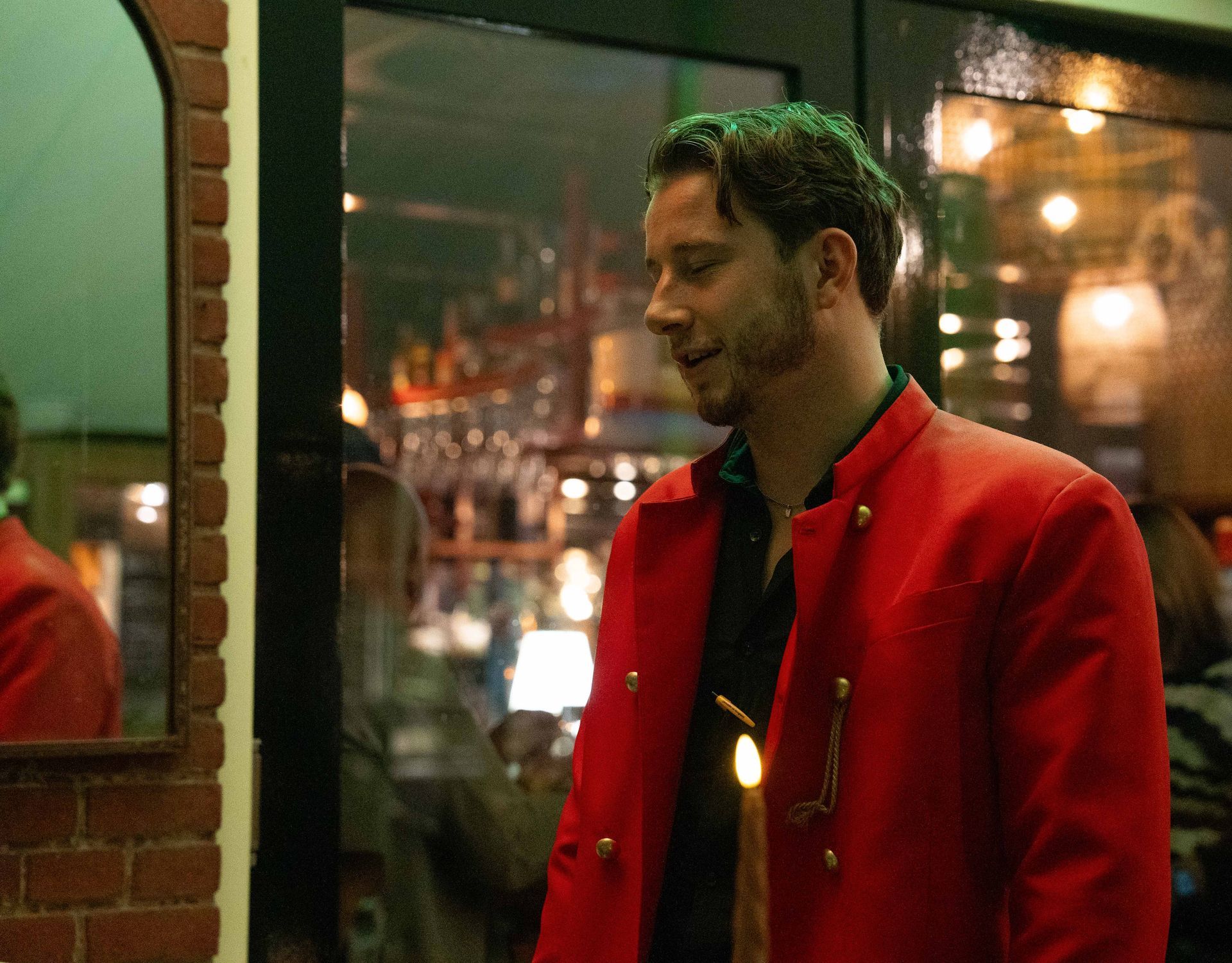 Een man in een rood jasje staat voor een deur