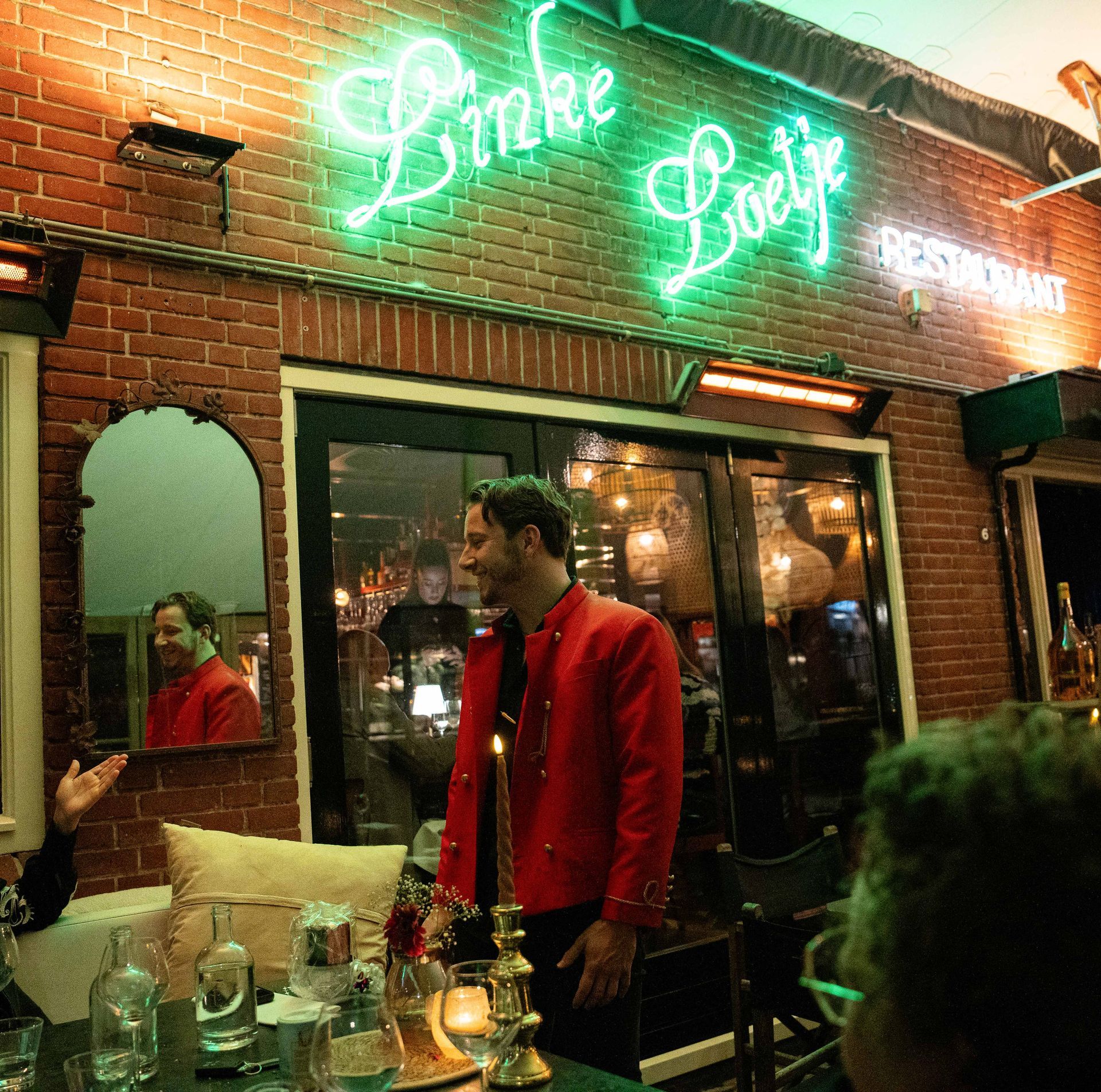 Een man in een rood jasje staat voor een restaurant genaamd linke