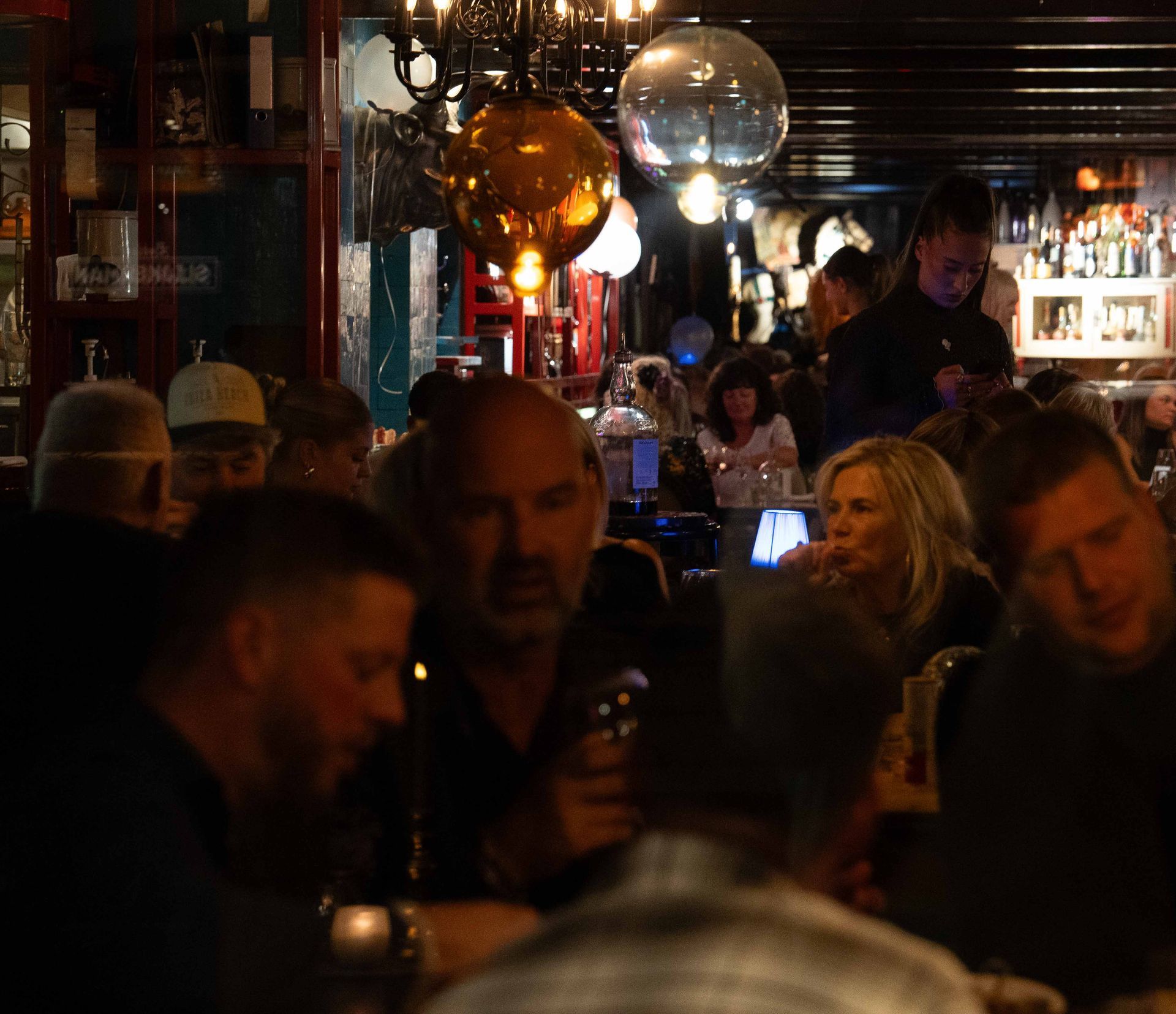 Een groep mensen zit aan tafels in een donkere kamer. Bij Linke Loetje