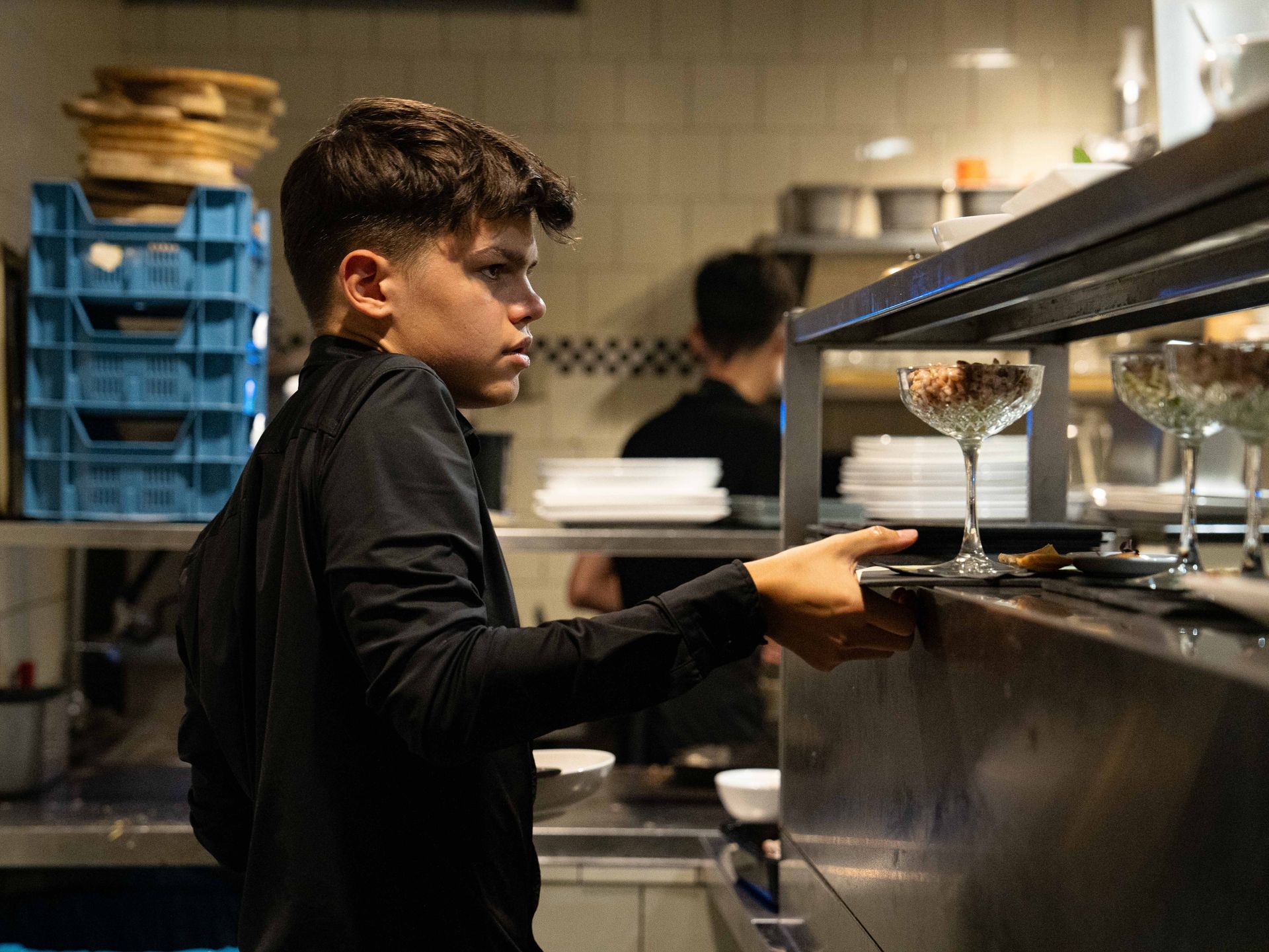 Een jonge jongen staat in de keuken met een dienblad met eten in zijn handen.