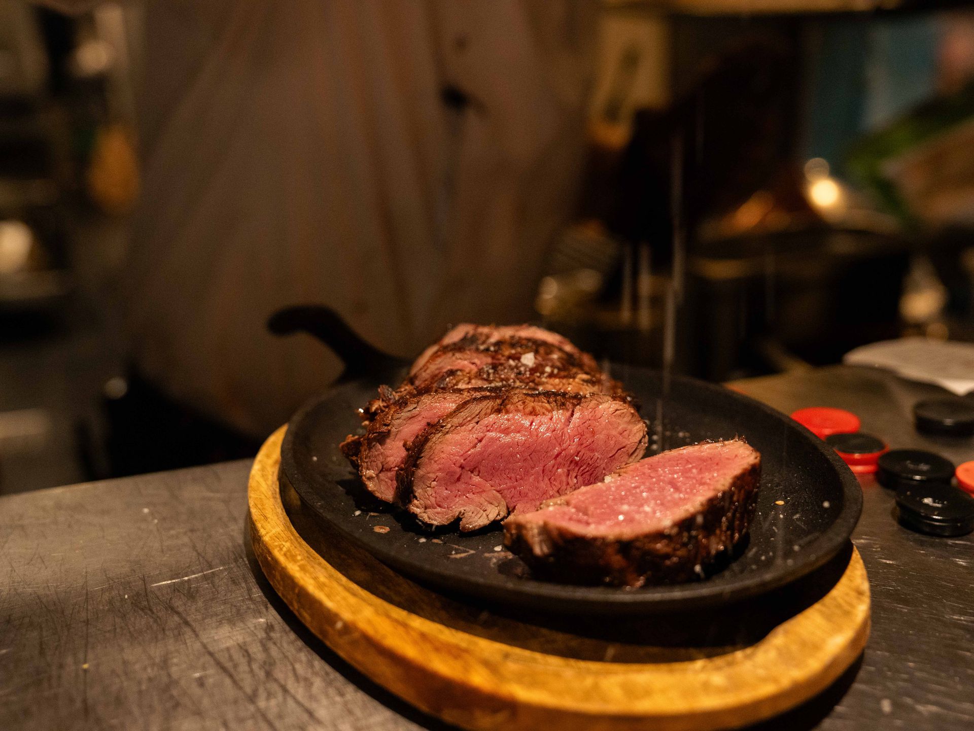 Een biefstuk wordt in plakjes gesneden op een pan op een houten snijplank. . Bij Linke Loetje