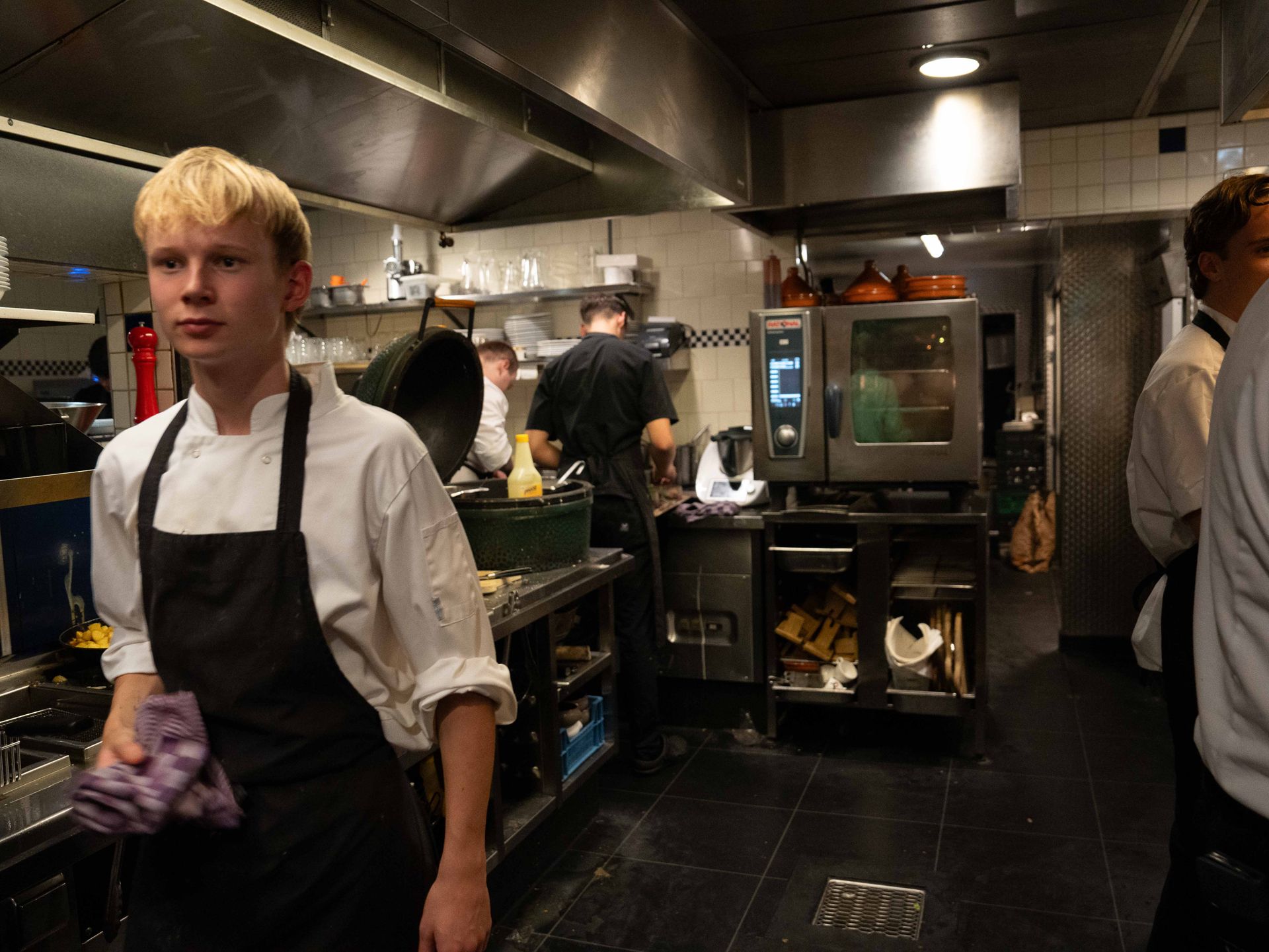 Een man met een schort staat in een keuken.. Bij Linke Loetje