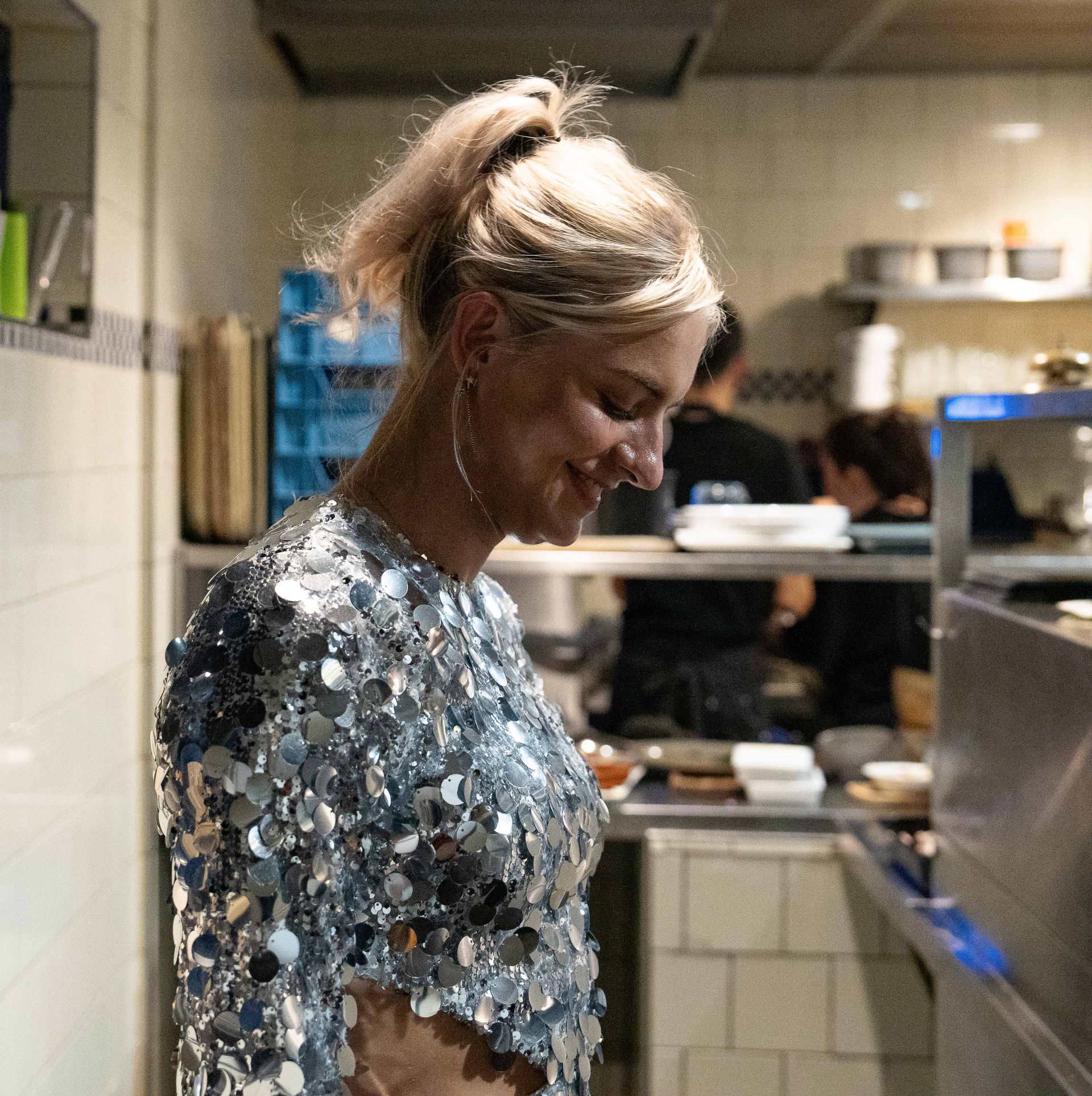 Een vrouw in een met pailletten bezette top staat in een keuken