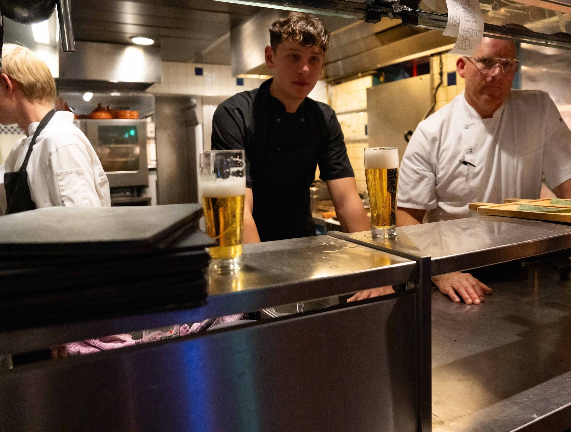 Drie mannen staan ​​in de keuken met glazen bier op het aanrecht.
