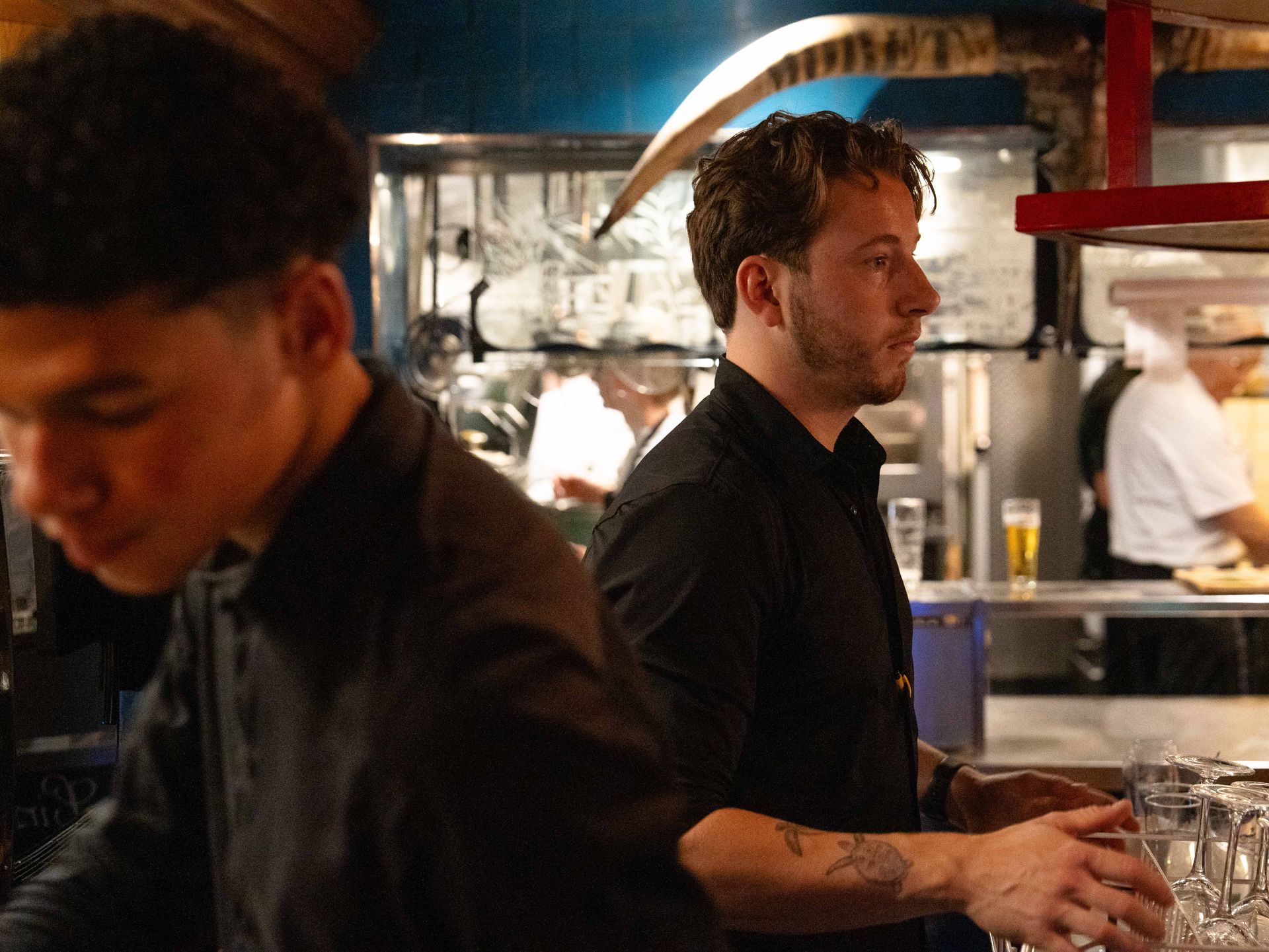 Een man in een zwart shirt staat naast een andere man in de keuken.. Bij Linke Loetje