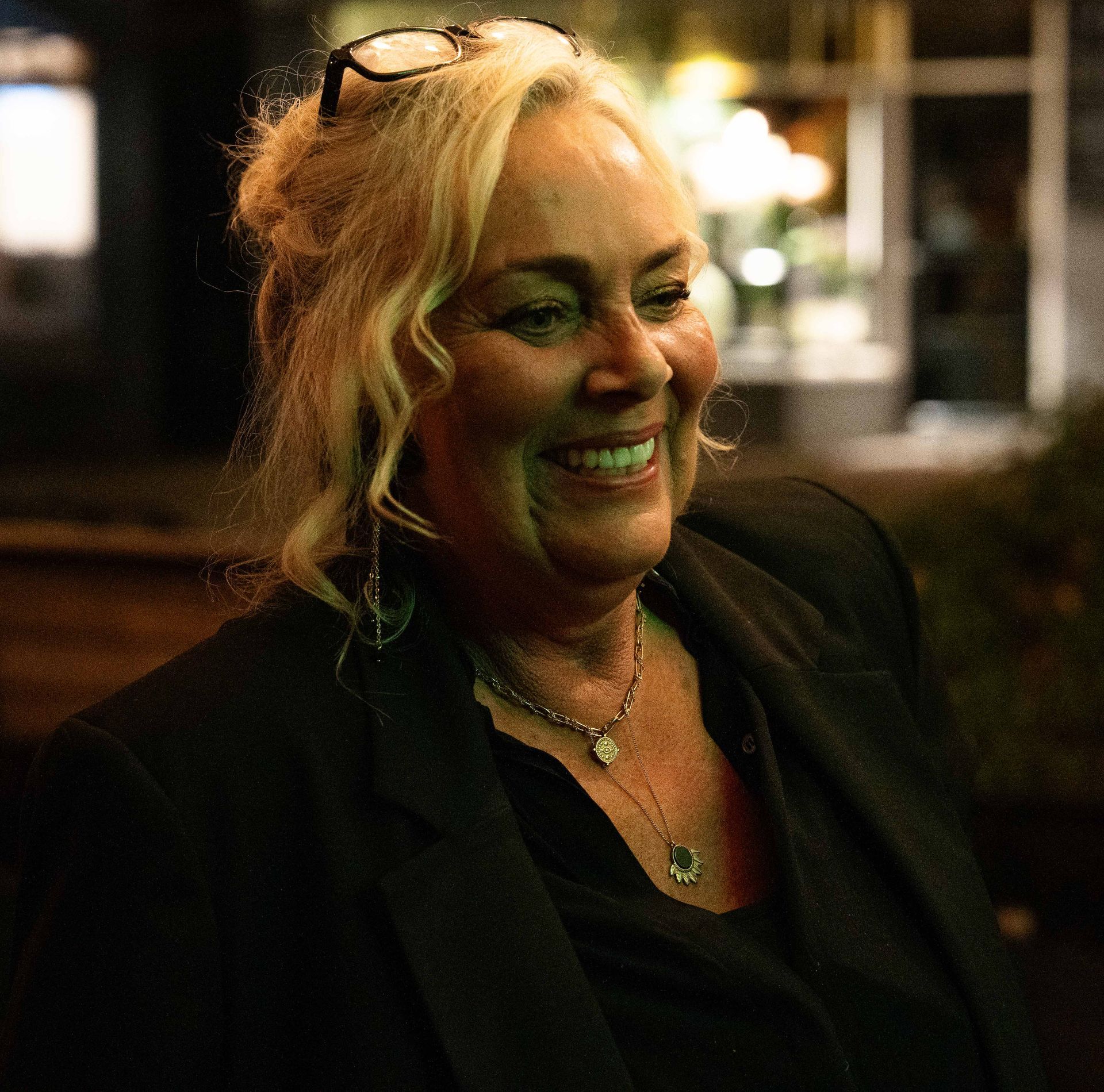 Een vrouw met een zonnebril en een ketting lacht