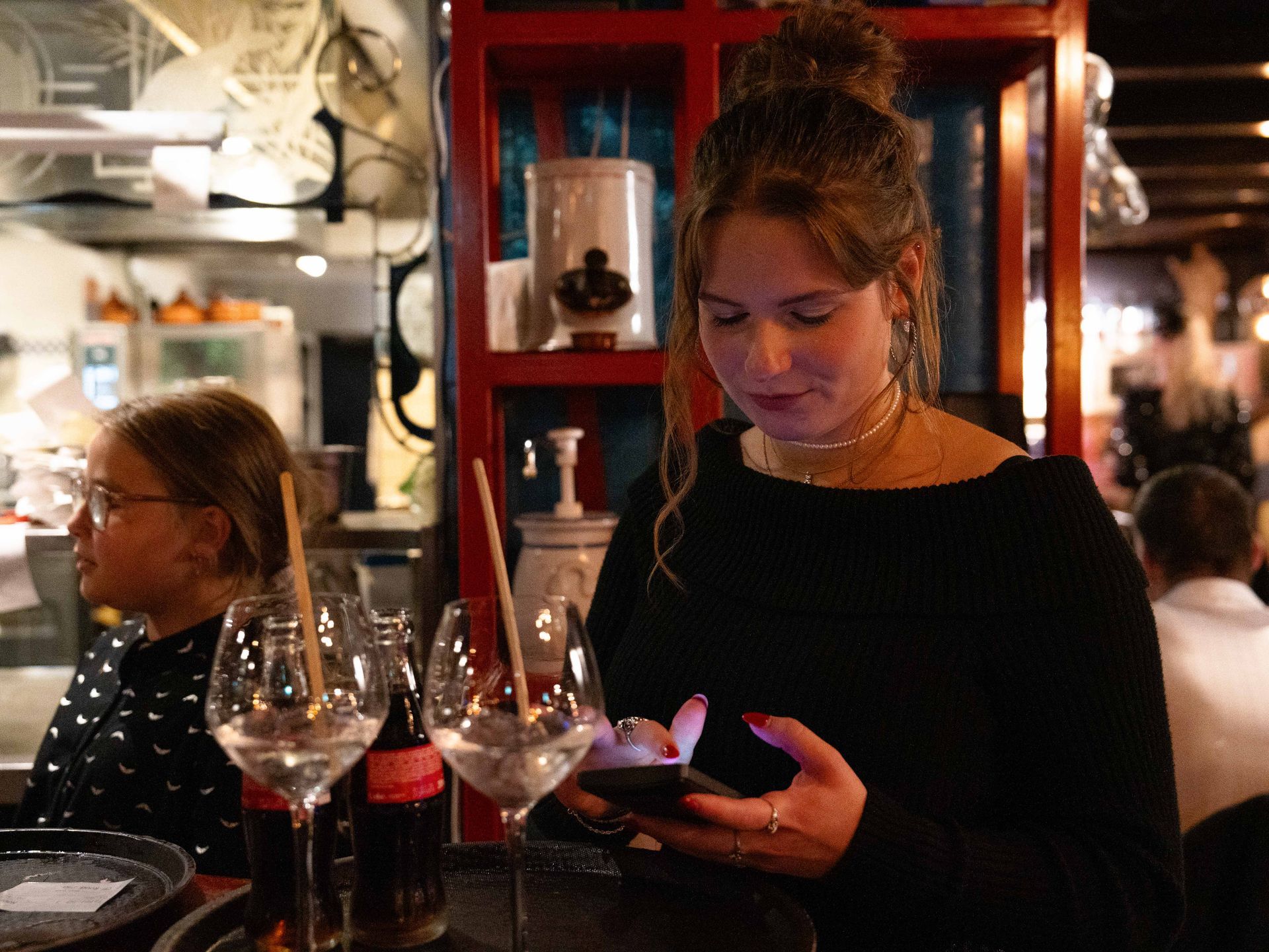 Een vrouw kijkt op haar telefoon in een restaurant. . Bij Linke Loetje