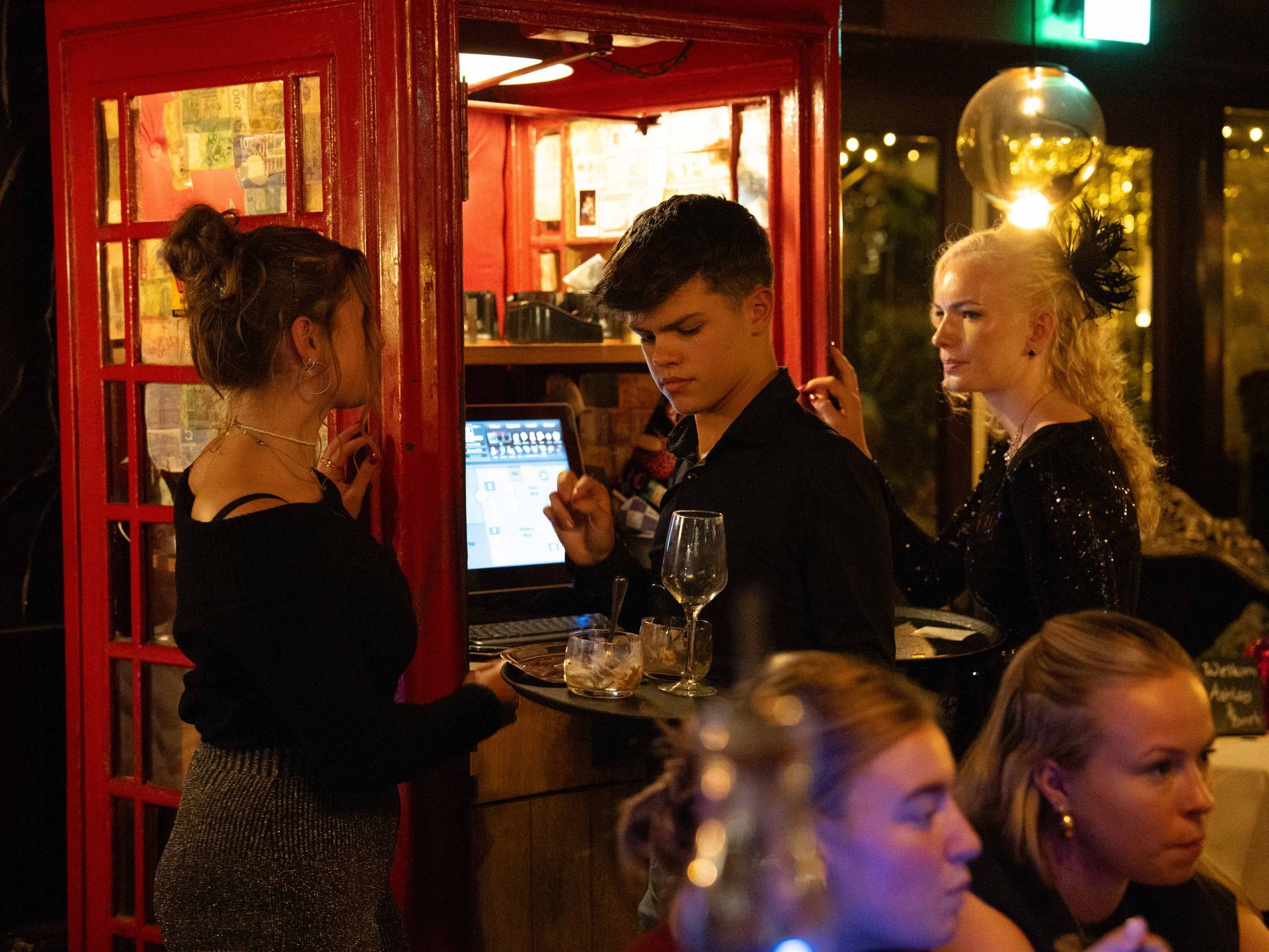 Een groep mensen zit in een rode telefooncel.. Bij Linke Loetje