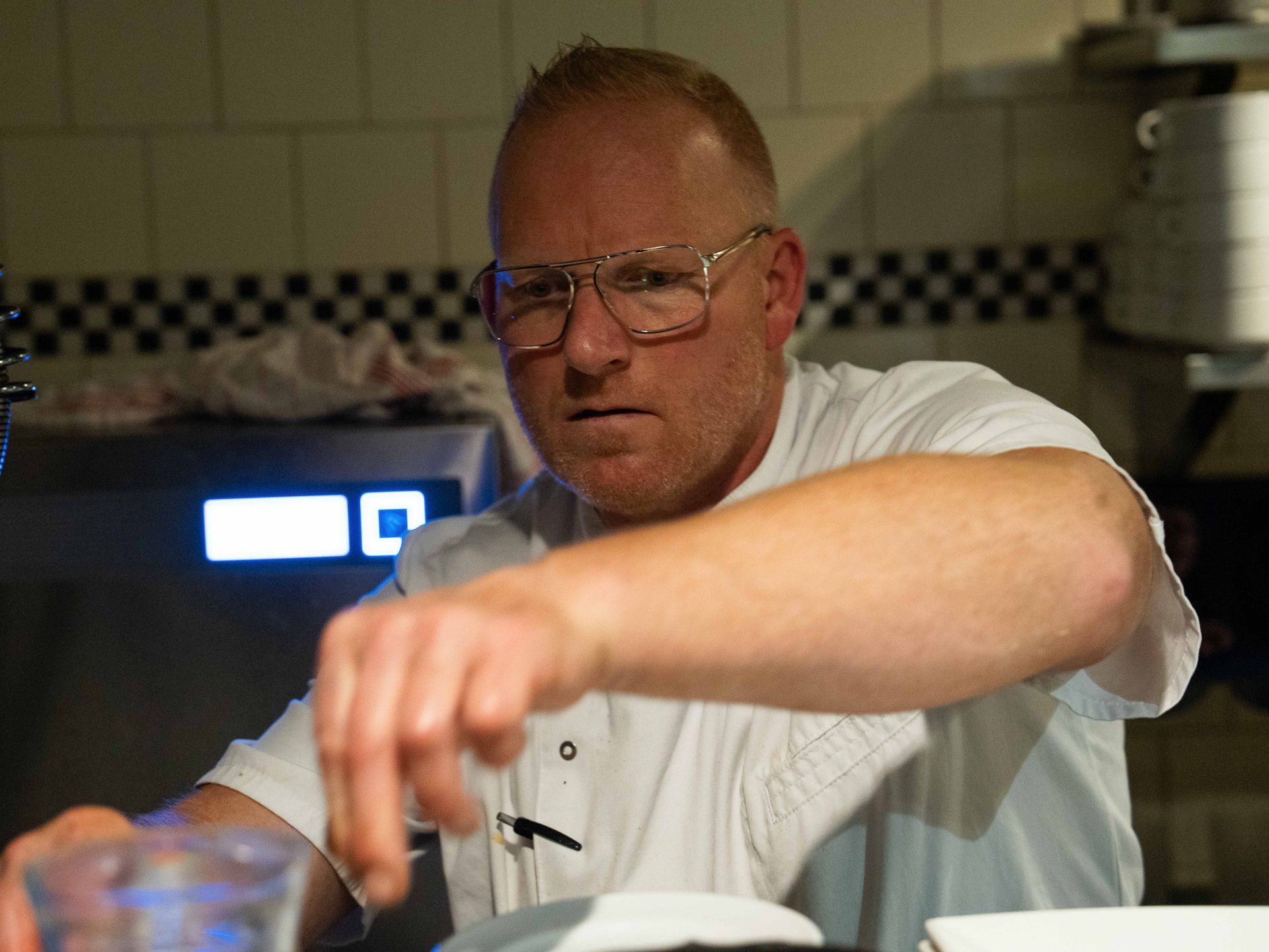 Een man met een bril en een wit overhemd bereidt eten in een keuken  bij Linke Loetje