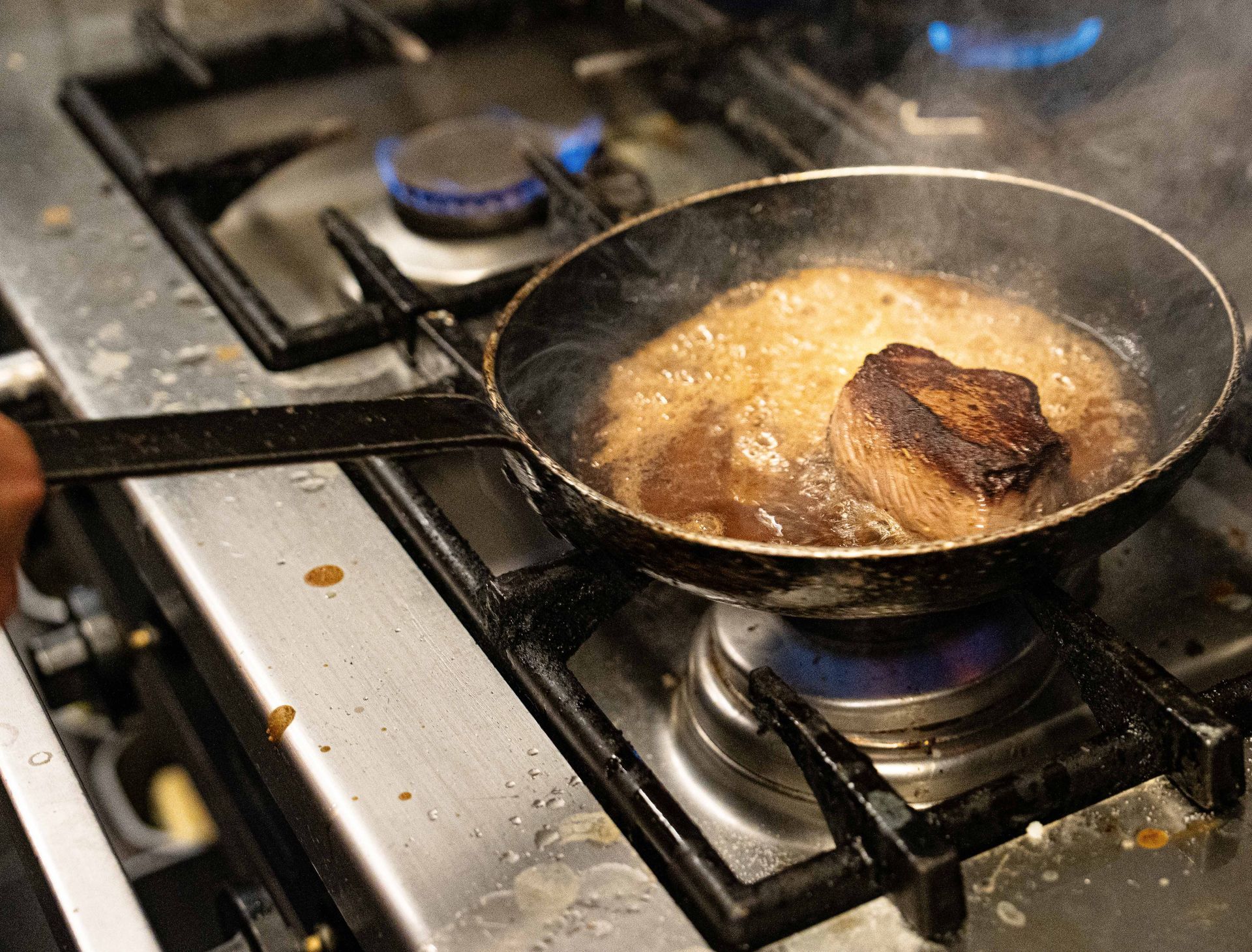 Een koekenpan gevuld met vlees kookt op een fornuis.
