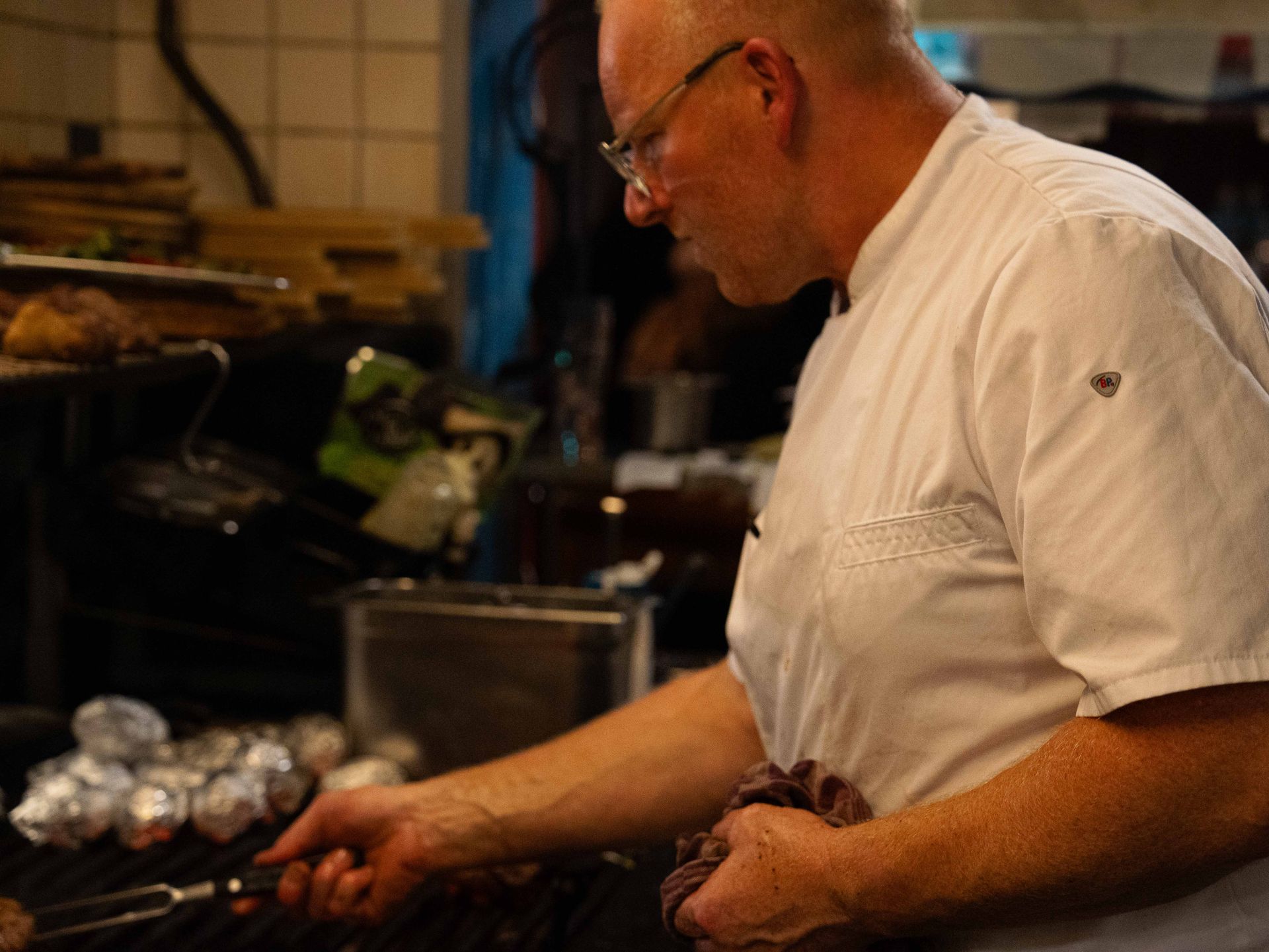 Een man kookt eten op een grill in een keuken.