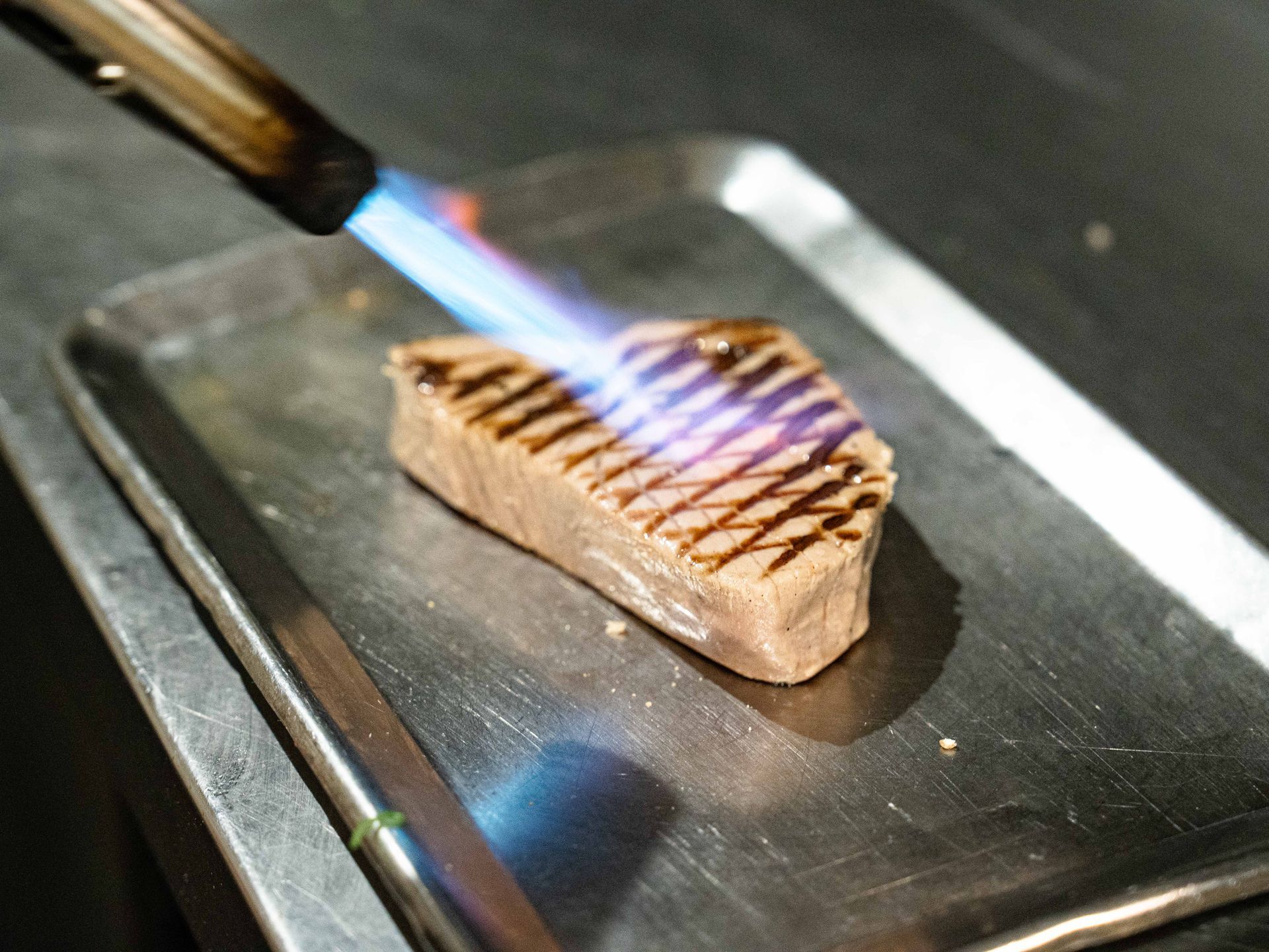 Een stuk vlees wordt op een dienblad gegrild met een aansteker.