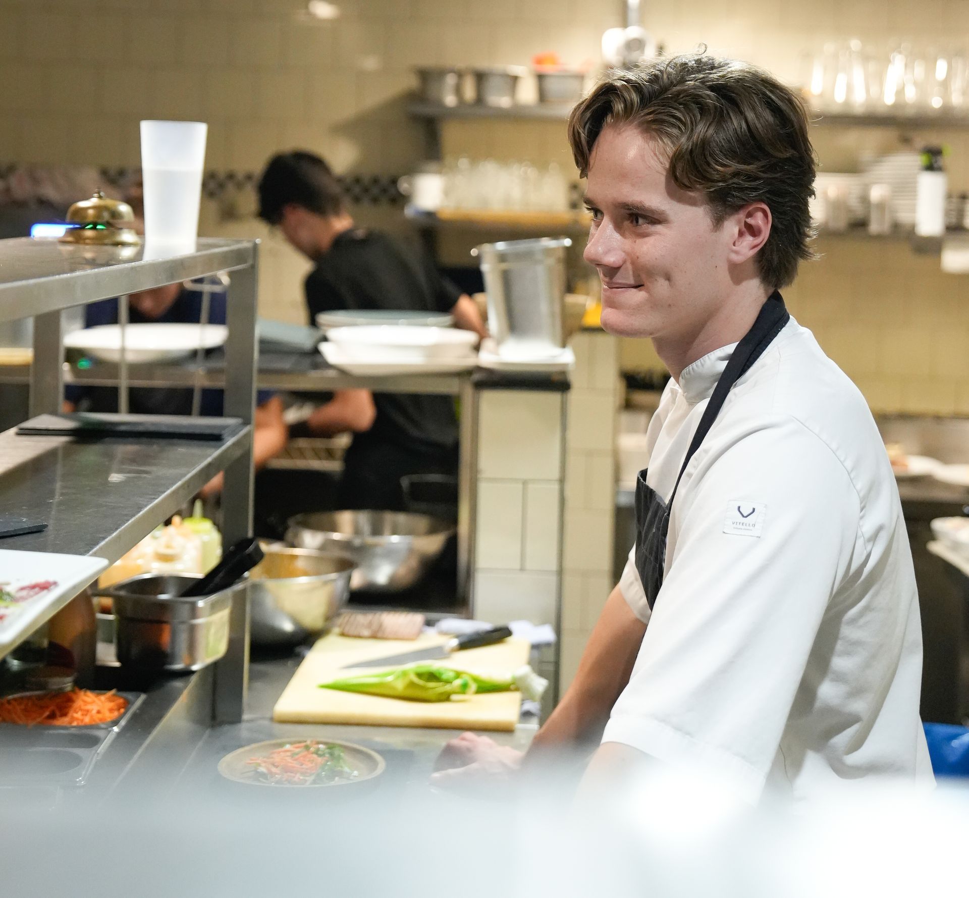 Een man met een schort zit aan een aanrecht in een keuken. Bij Linke Loetje