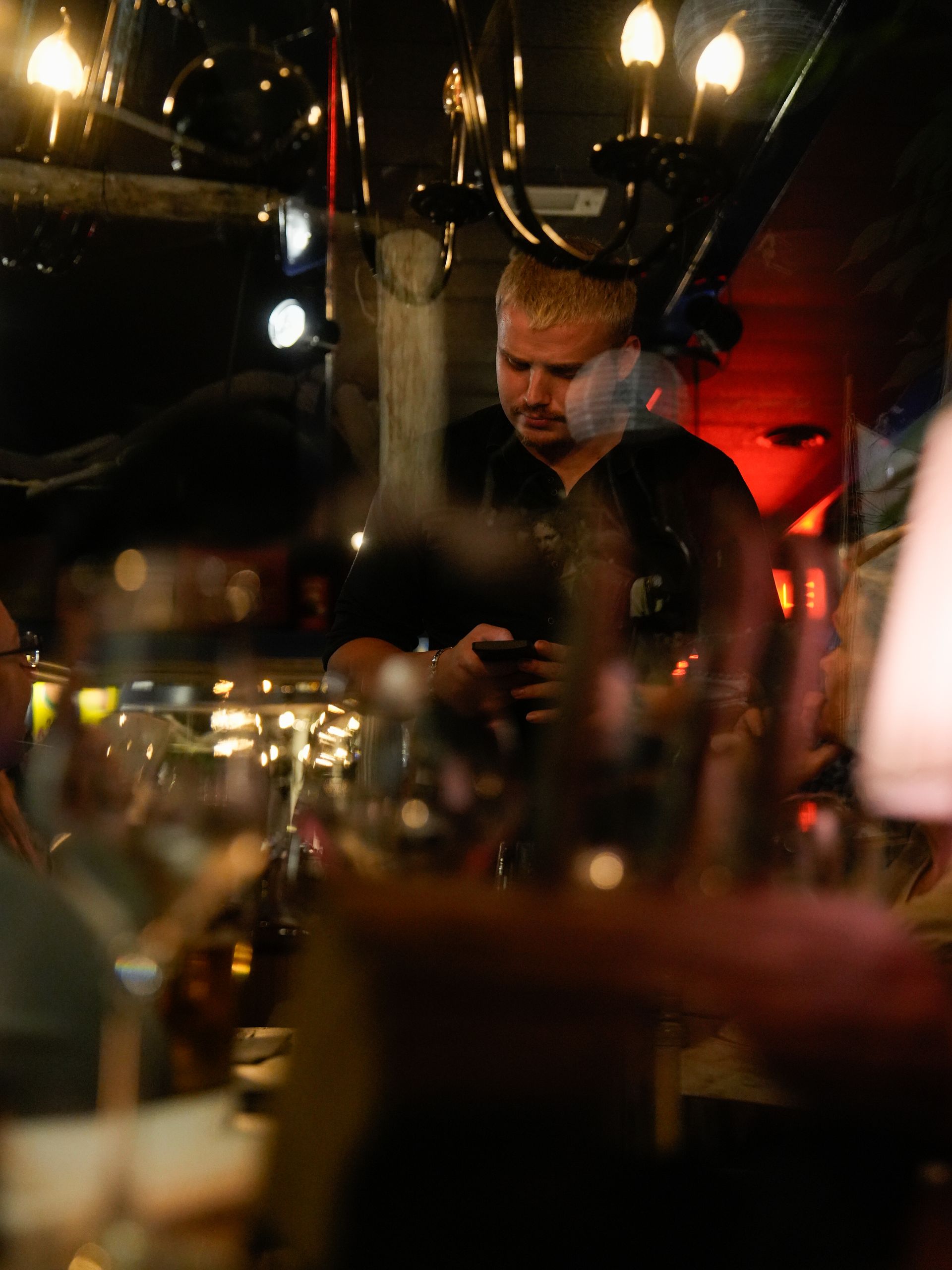 Een man kijkt in een donkere kamer naar zijn telefoon. Bij Linke Loetje