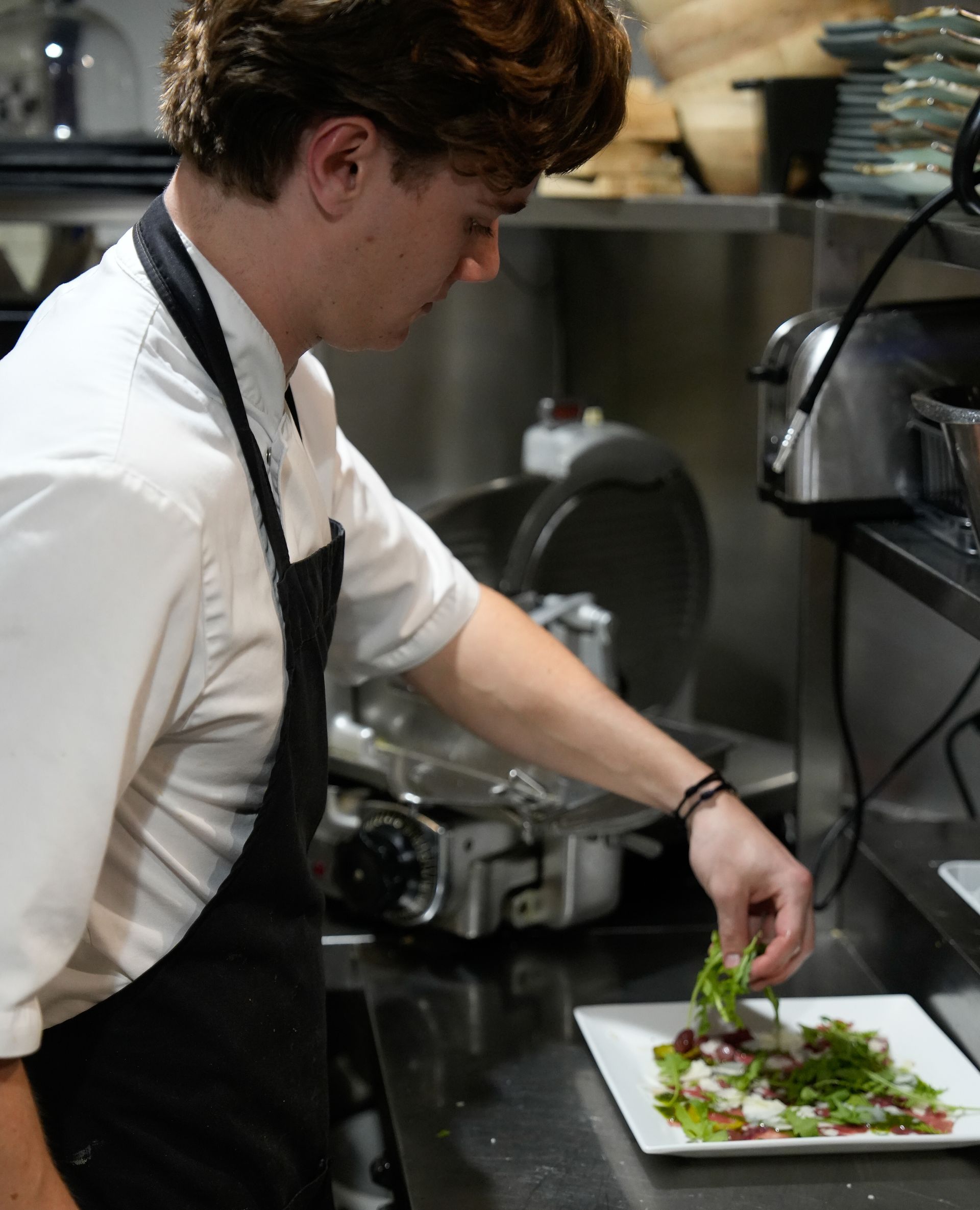 Een man met een schort bereidt eten in een keuken. Bij Linke Loetje