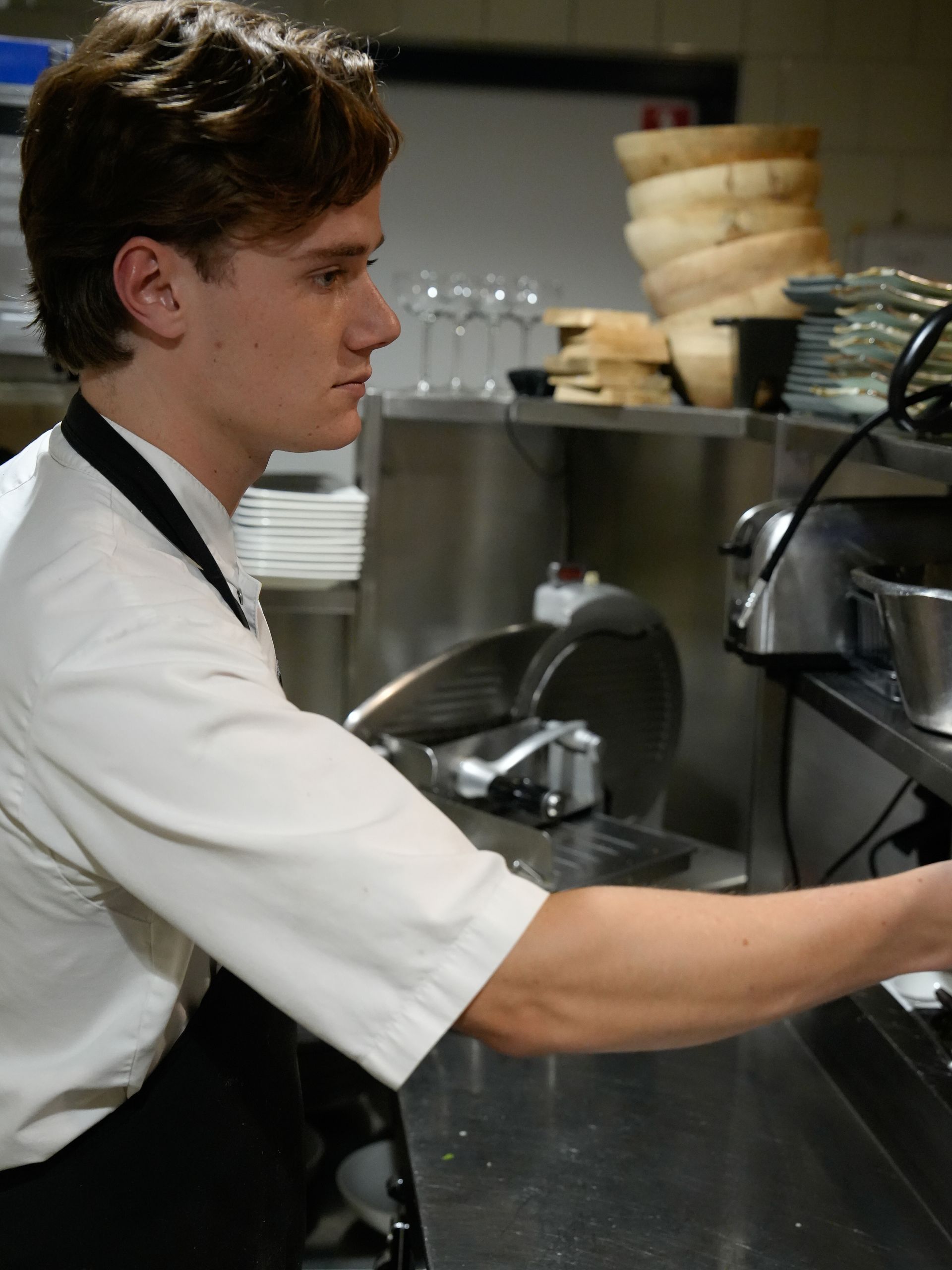 Een man in een wit overhemd werkt in een keuken. Bij Linke Loetje