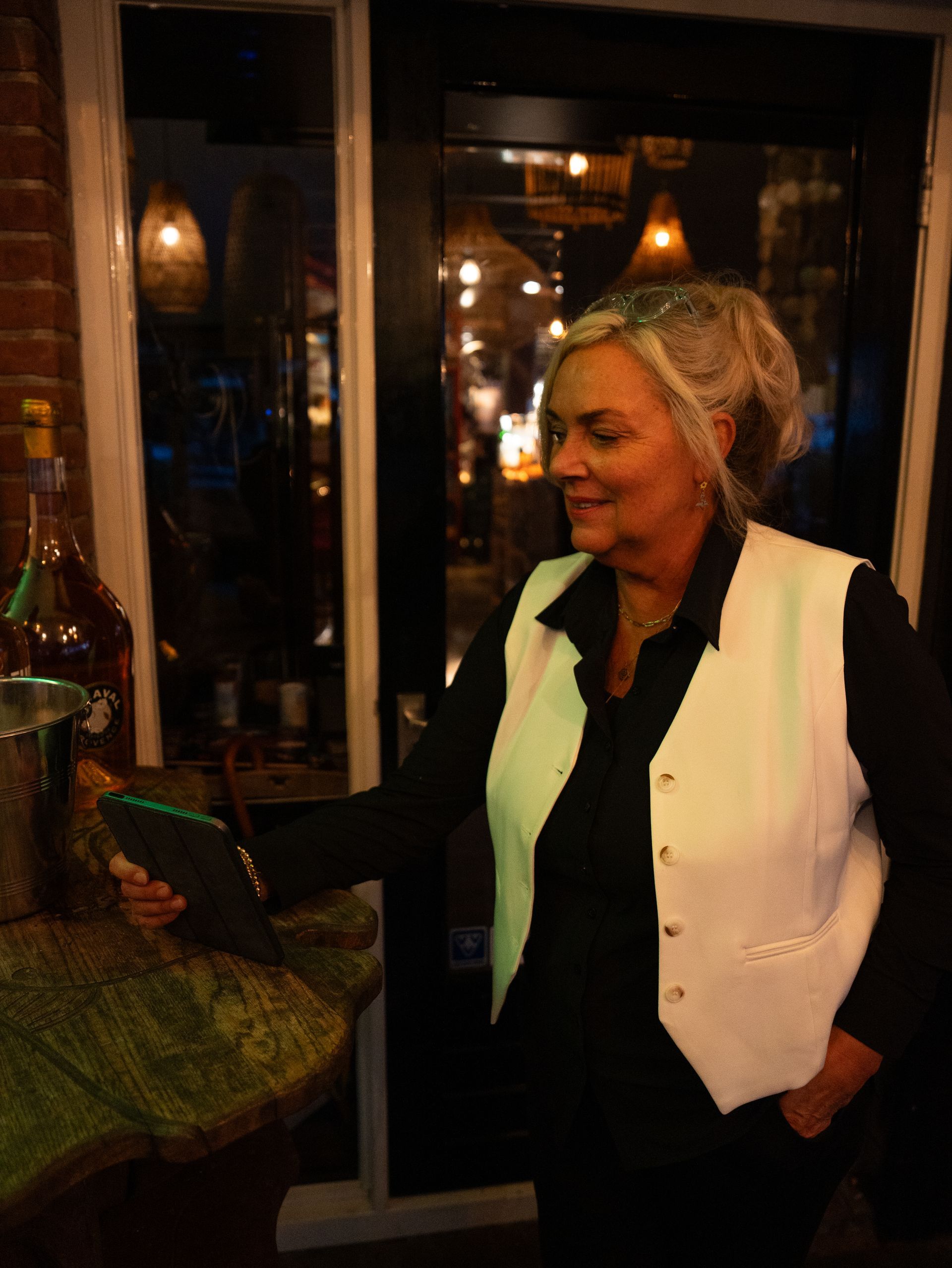 Een vrouw in een wit vest houdt een tablet vast . Bij Linke Loetje