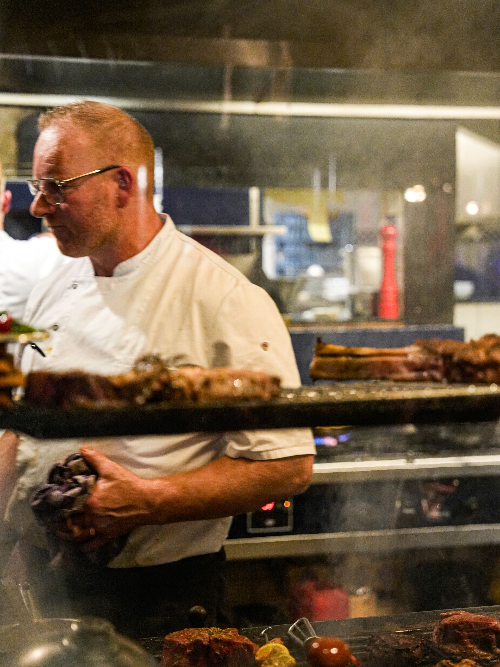 Een man in een koksuniform bereidt eten in een keuken. Bij Linke Loetje