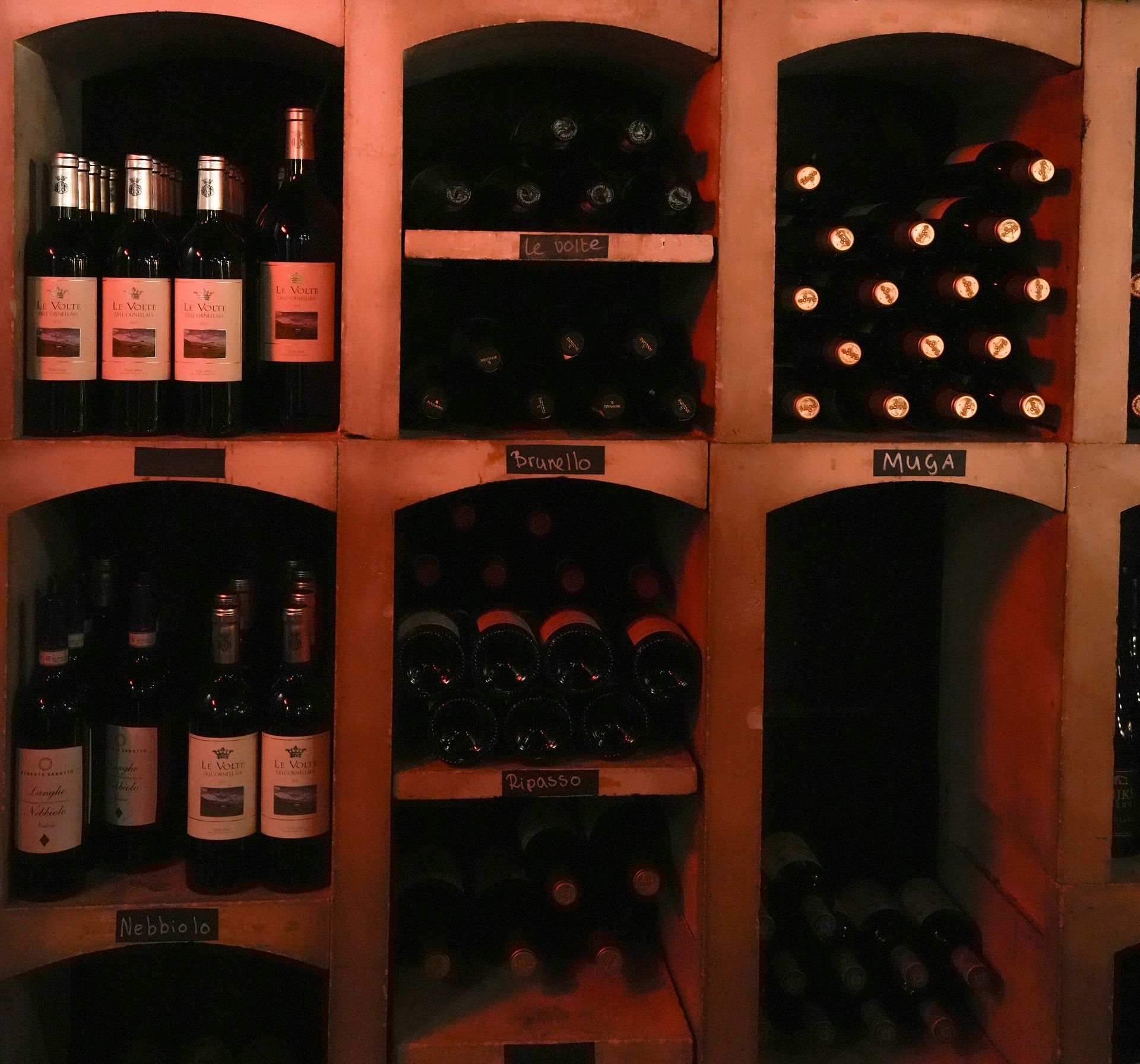 Een rij planken vol met flessen wijn, waaronder een fles ribera. . Bij Linke Loetje