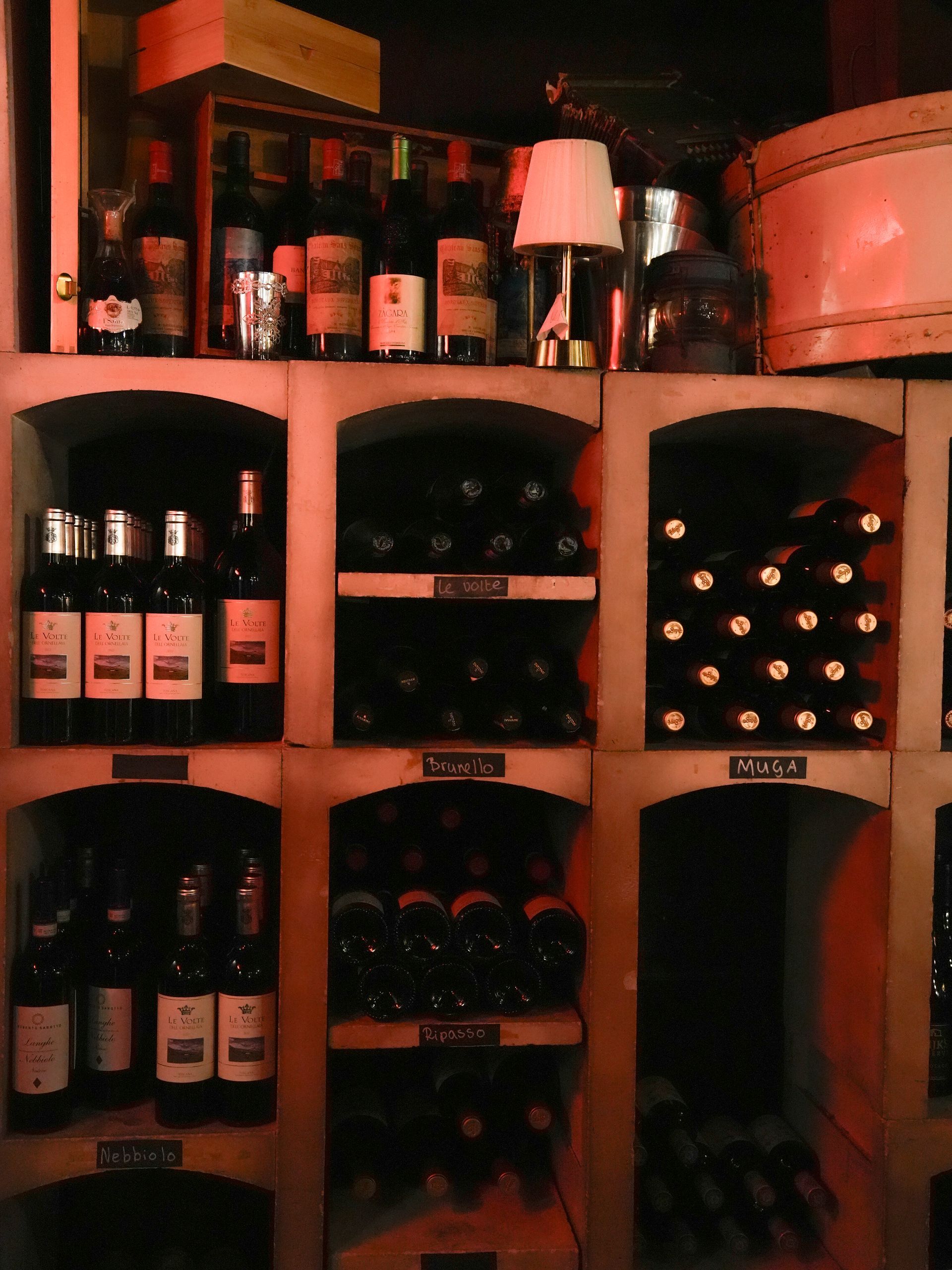 Er staan ​​meerdere flessen wijn op planken, waarvan er één is gemarkeerd met 'secco' . Bij Linke Loetje