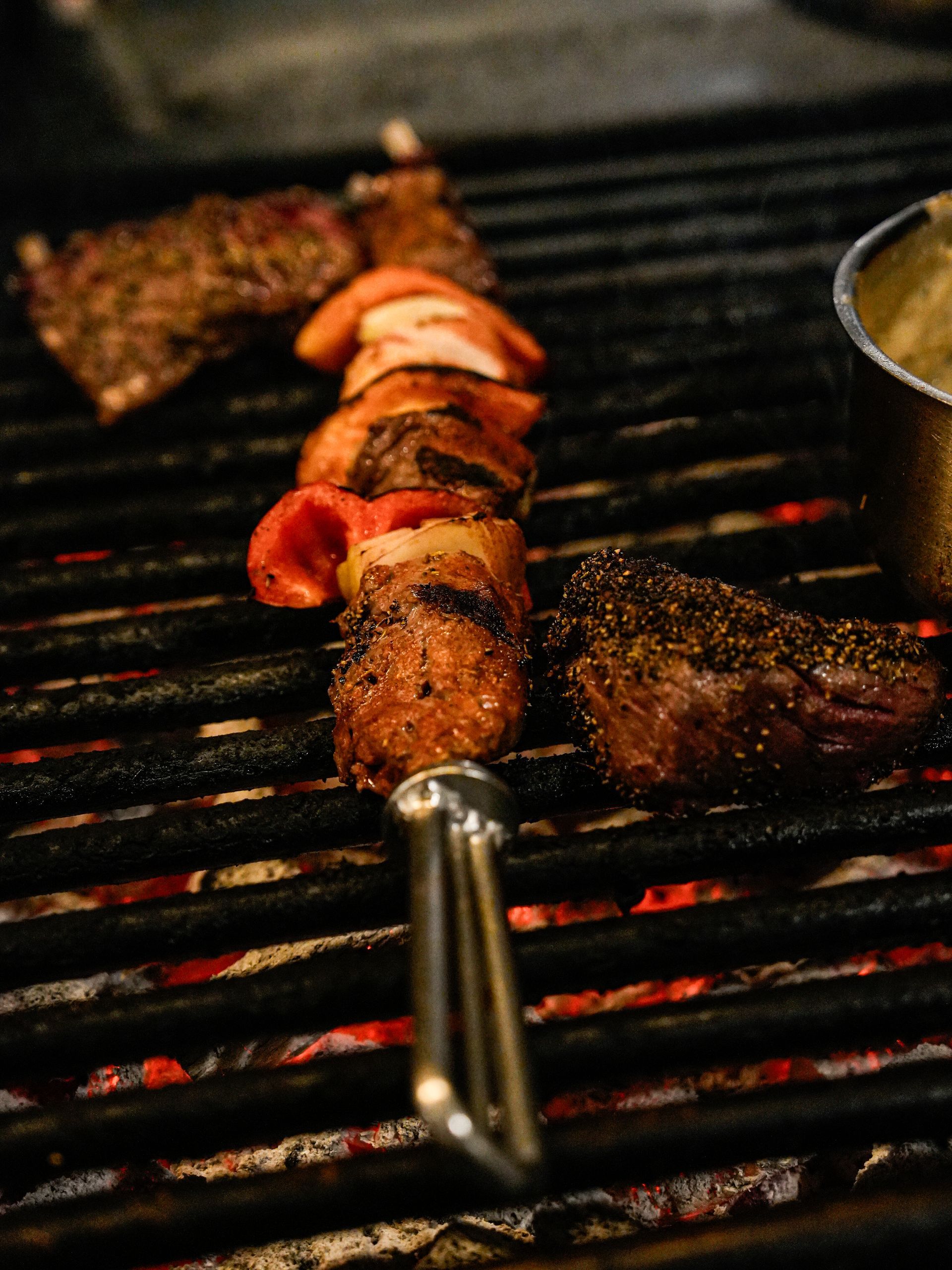 Een spiesje vlees ligt op een grill.. Bij Linke Loetje