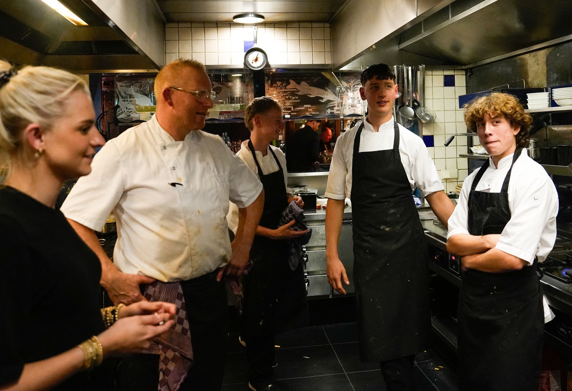 Een groep mensen staat in een keuken met elkaar te praten. . Bij Linke Loetje