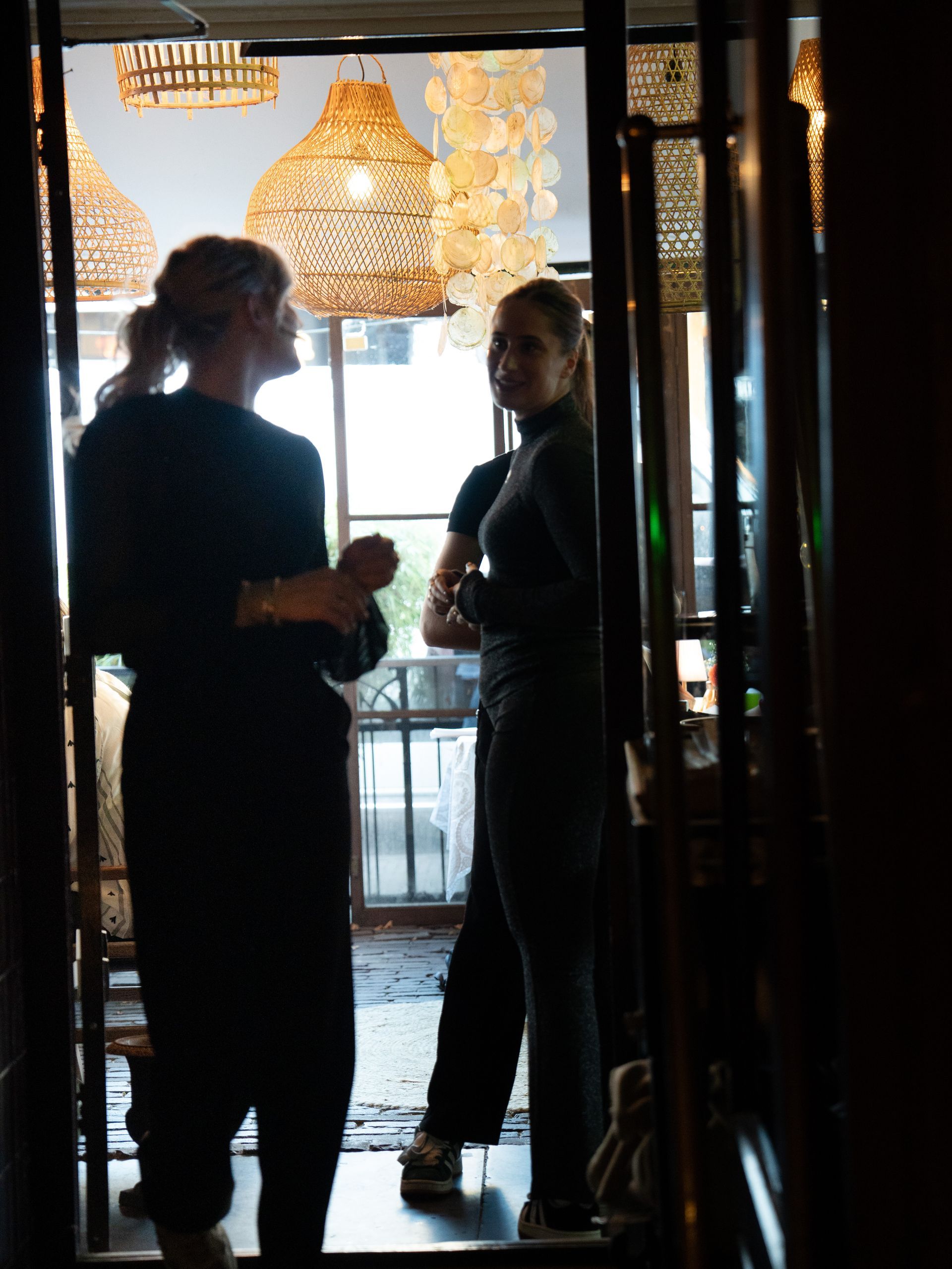 Twee vrouwen staan ​​in een deuropening en praten met elkaar. Bij Linke Loetje