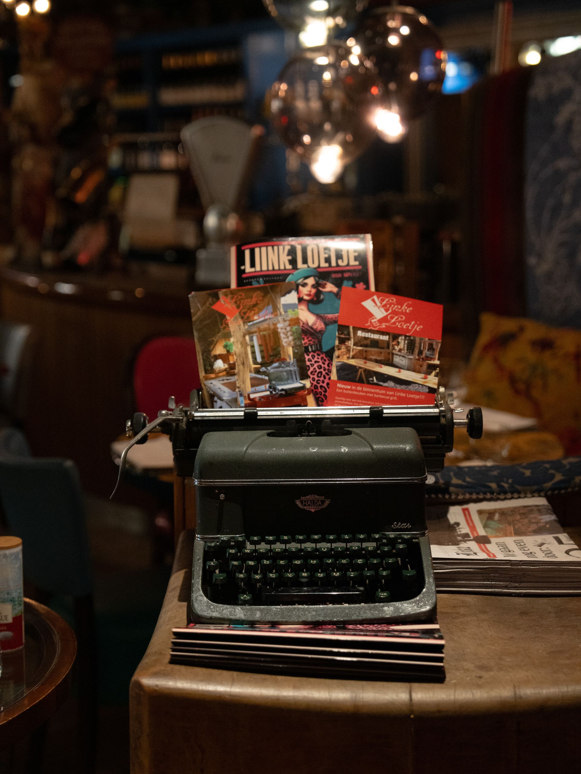 Er staat een typemachine op een tafel met daarop een tijdschrift waarop staat: levend leven. Bij Linke Loetje