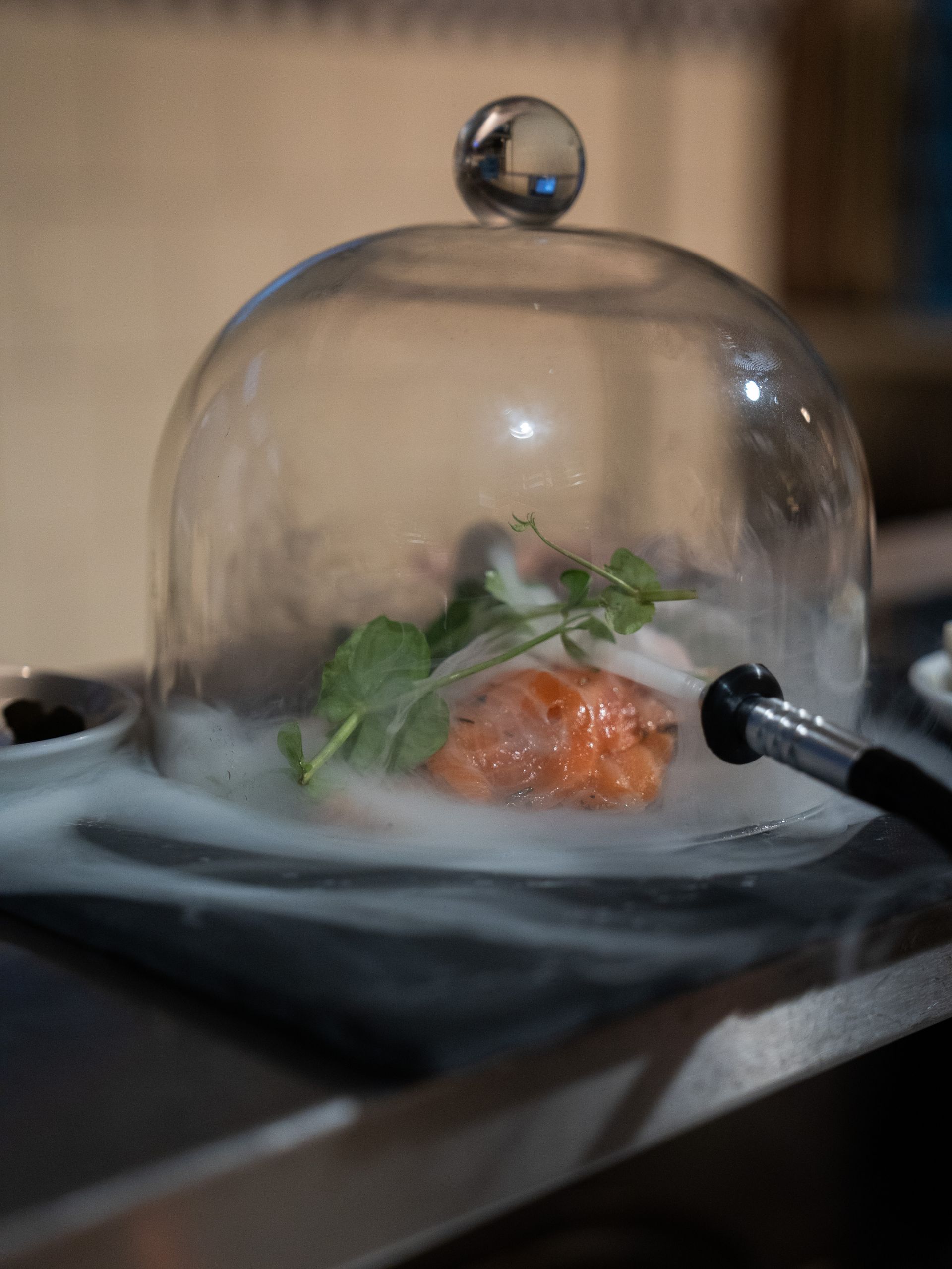 Een bord met eten onder een glazen koepel op een tafel.. Bij Linke Loetje