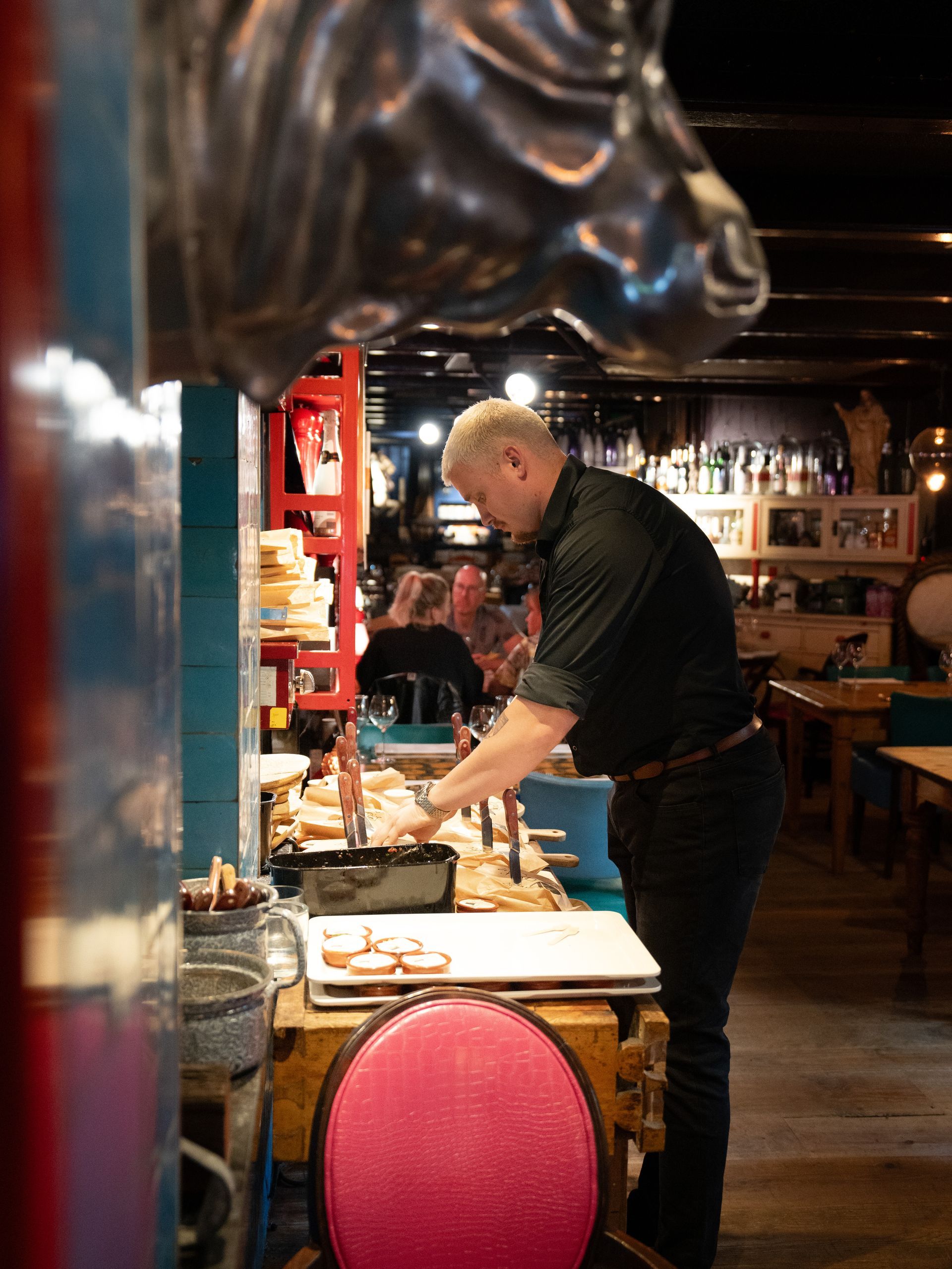 Een man staat aan een tafel in een restaurant.. Bij Linke Loetje