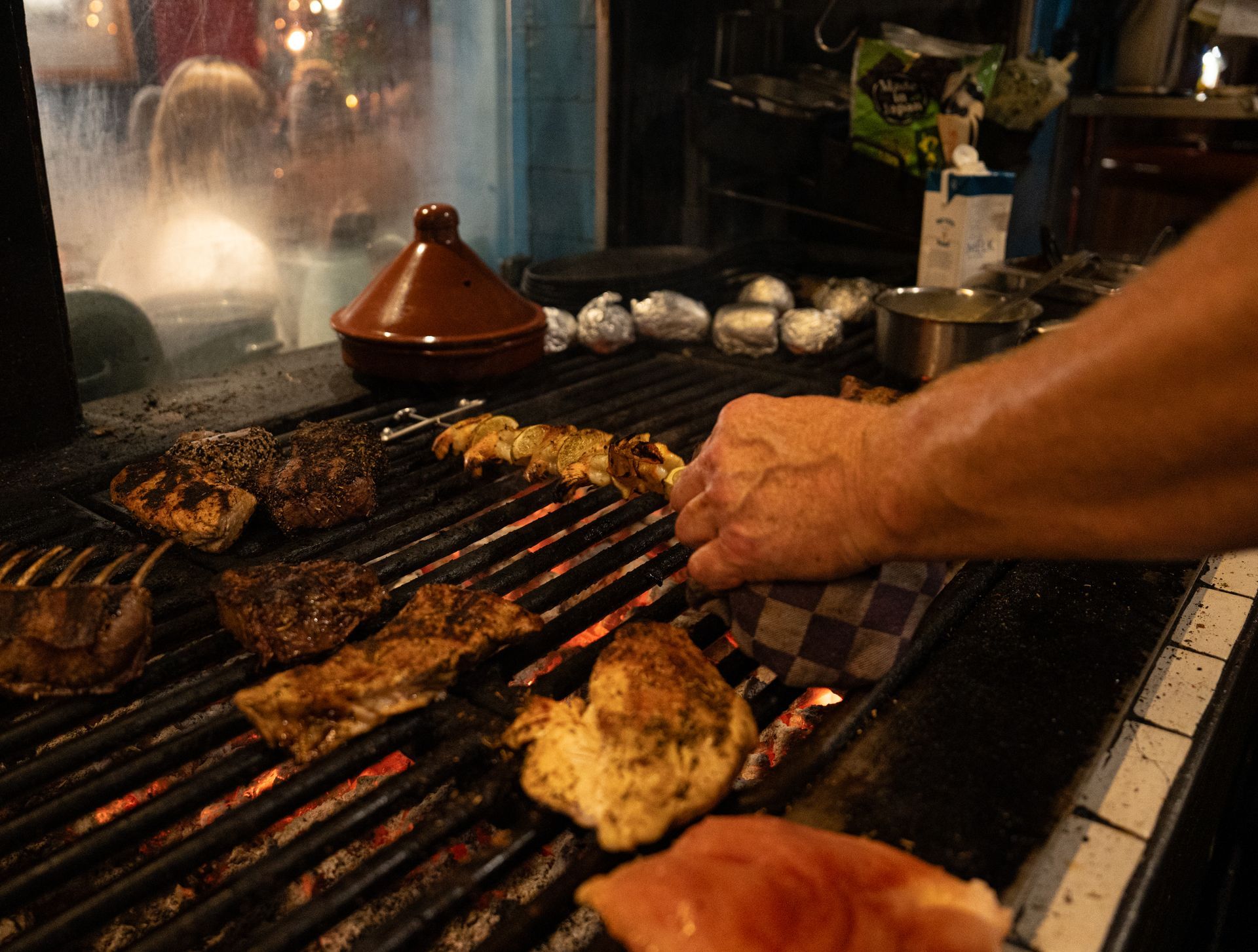 Iemand is vlees aan het grillen in een keuken.. Bij Linke Loetje