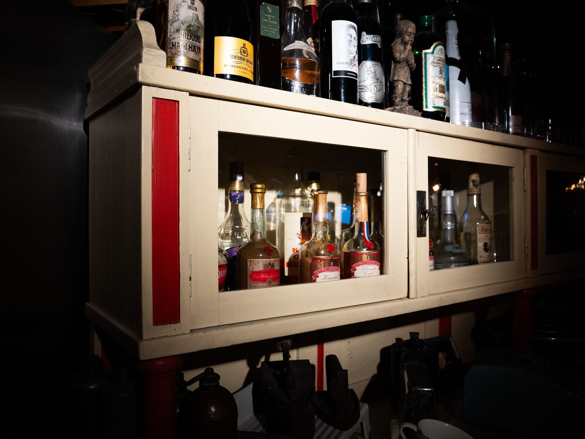 Een plank vol met flessen alcohol . Bij Linke Loetje