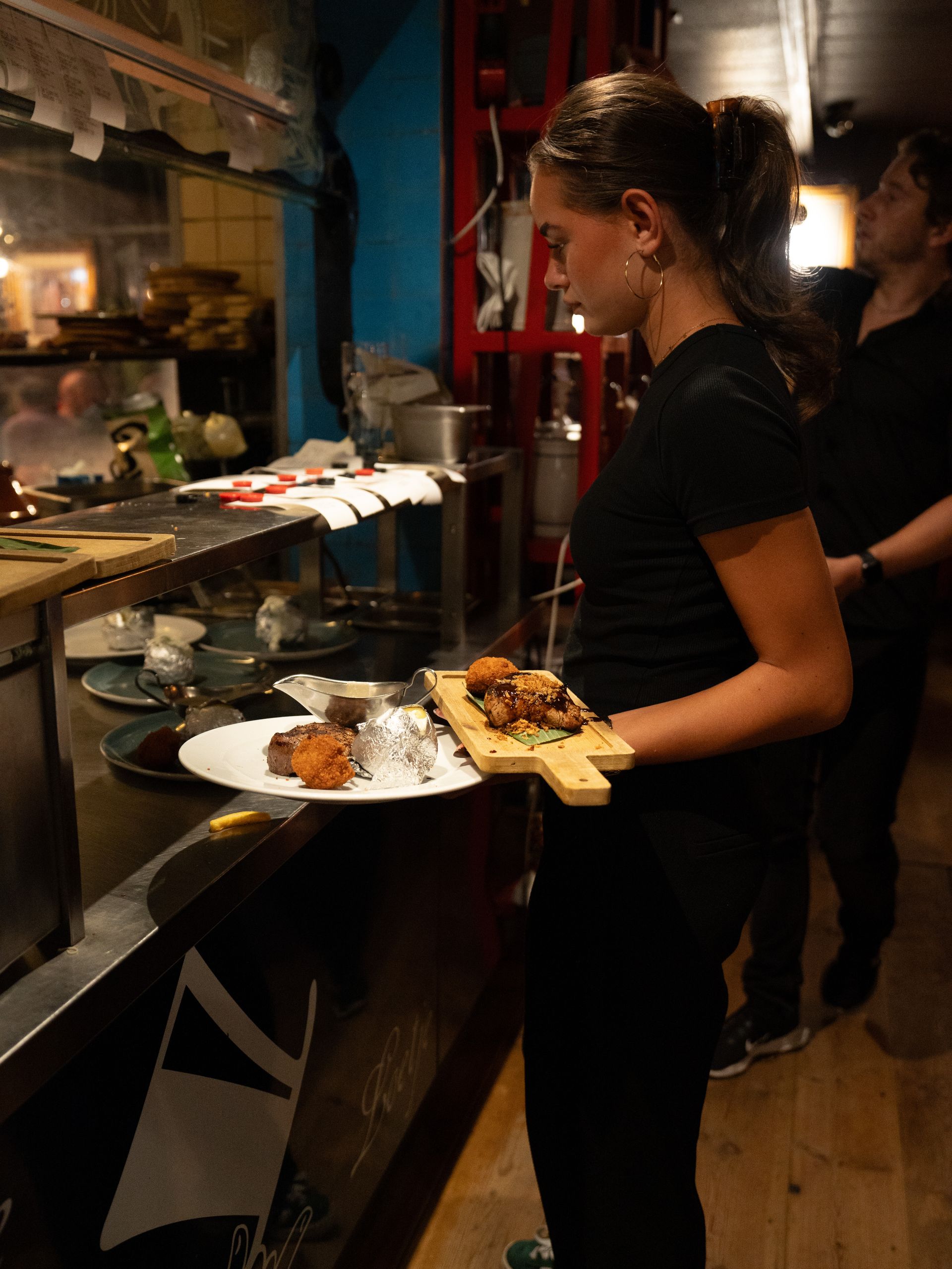 Een vrouw houdt een bord met eten vast in de keuken.. Bij Linke Loetje