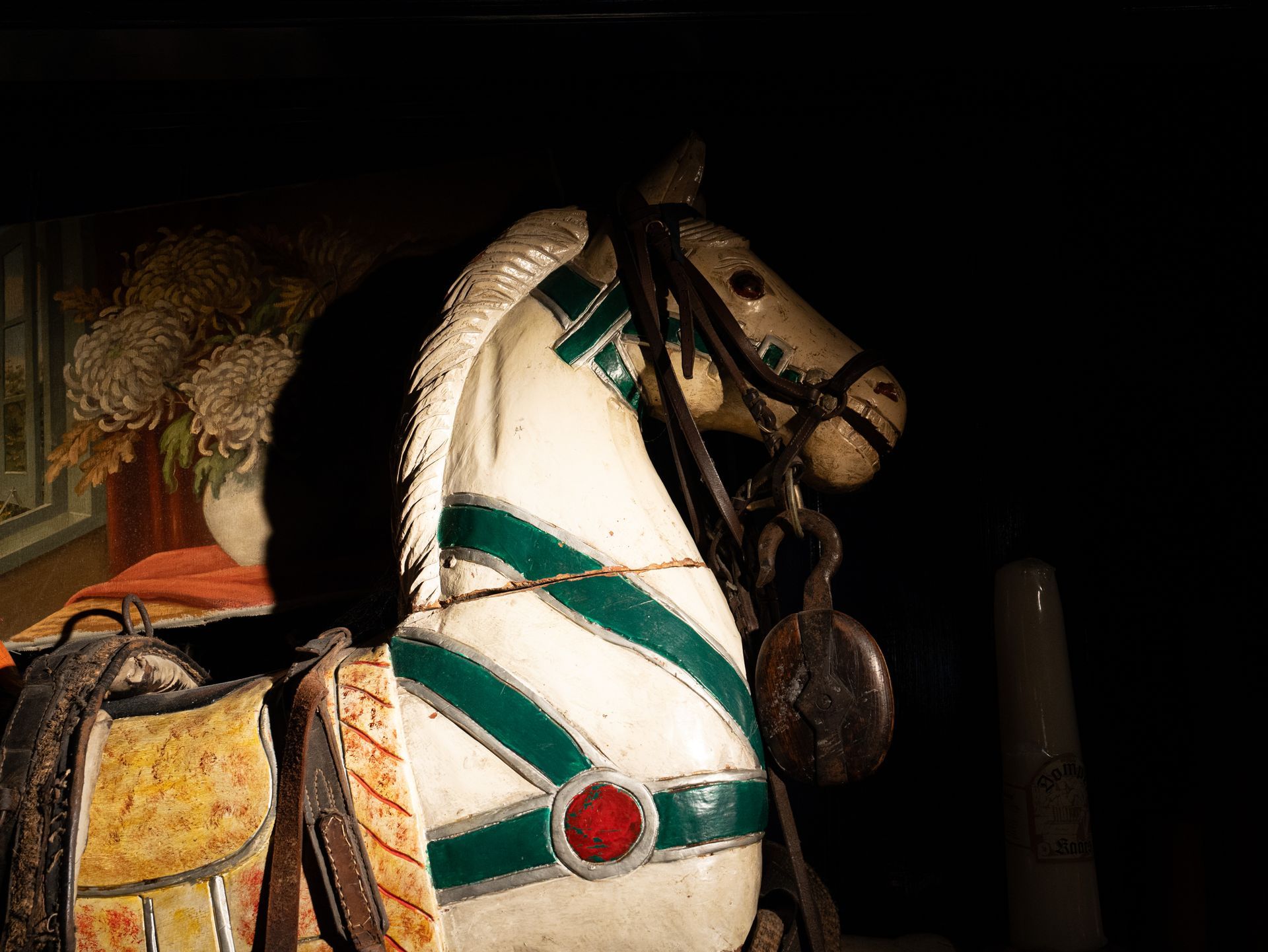 Een wit en groen schommelpaard met een hoofdstel en zadel. Bij Linke Loetje