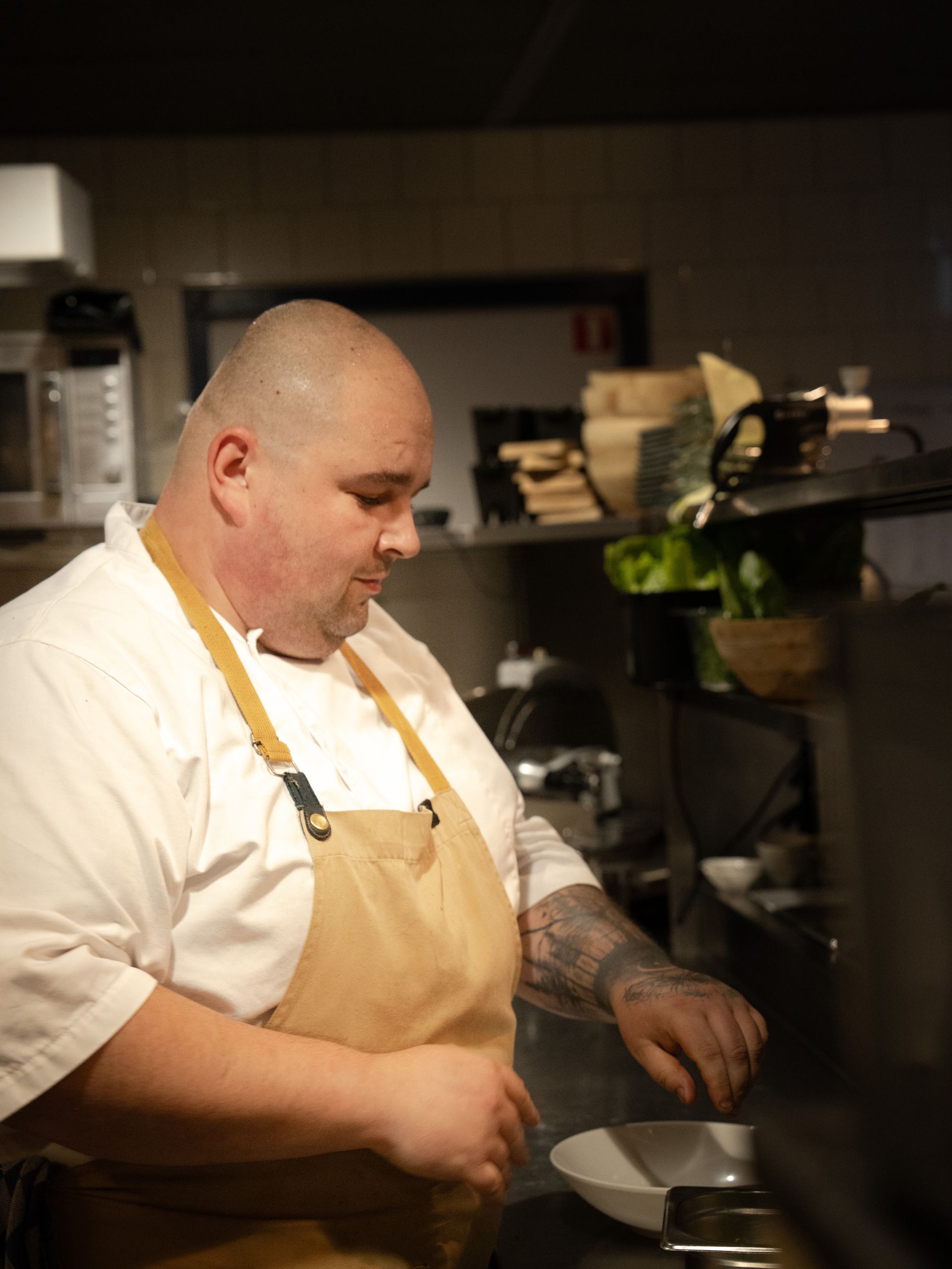 Een man met een schort bereidt eten in een keuken. Bij Linke Loetje