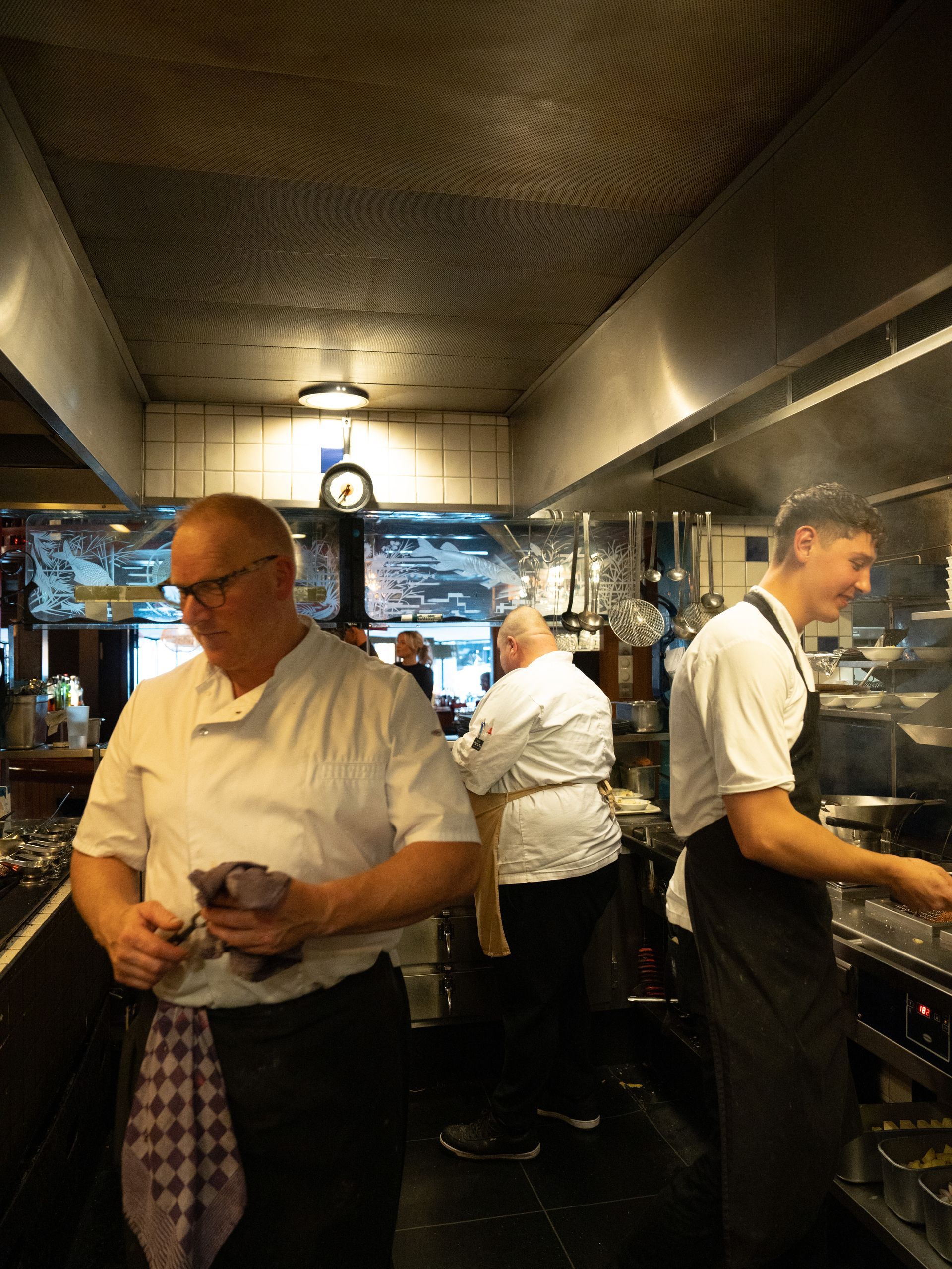 Een groep mannen staat in een keuken eten te bereiden.. Bij Linke Loetje