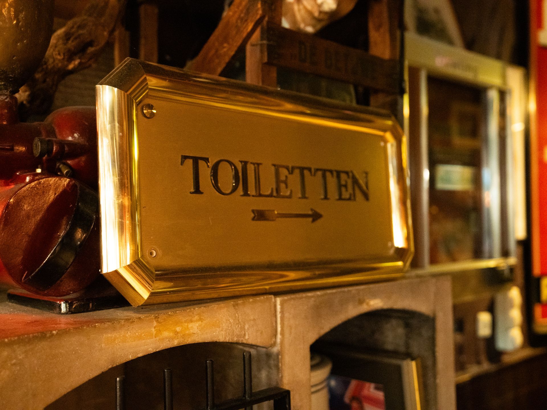 Een gouden bord met de tekst toiletten met een pijl die naar rechts wijst. Bij Linke Loetje