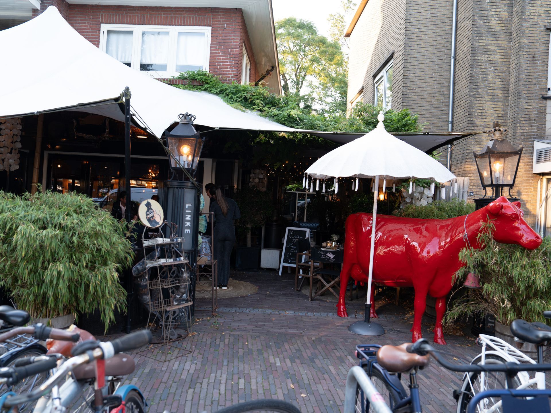 Een standbeeld van een rode koe staat voor een restaurant. Bij Linke Loetje
