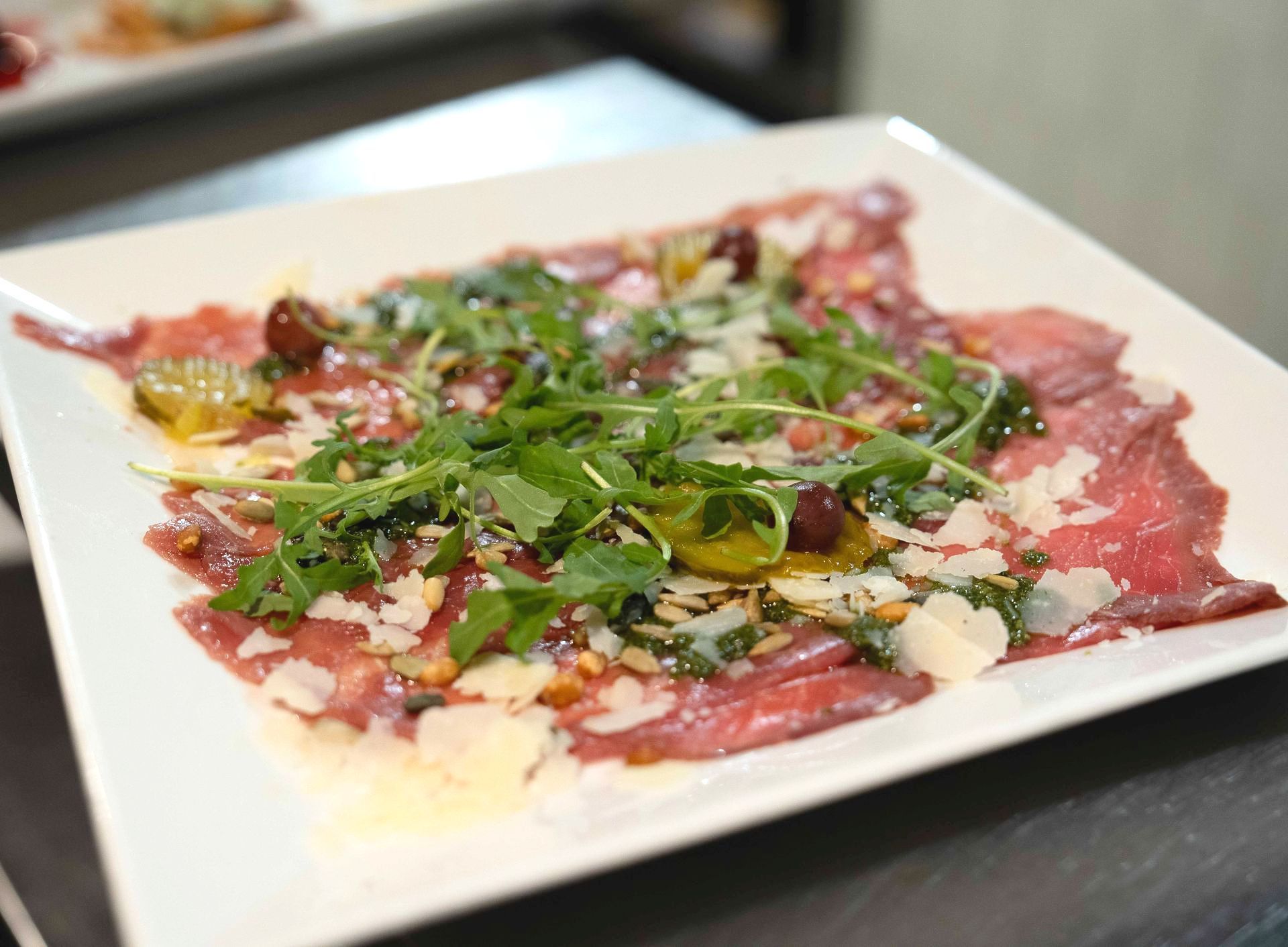 Een wit bord met vlees en groenten op een tafel. bij Linke Loetje