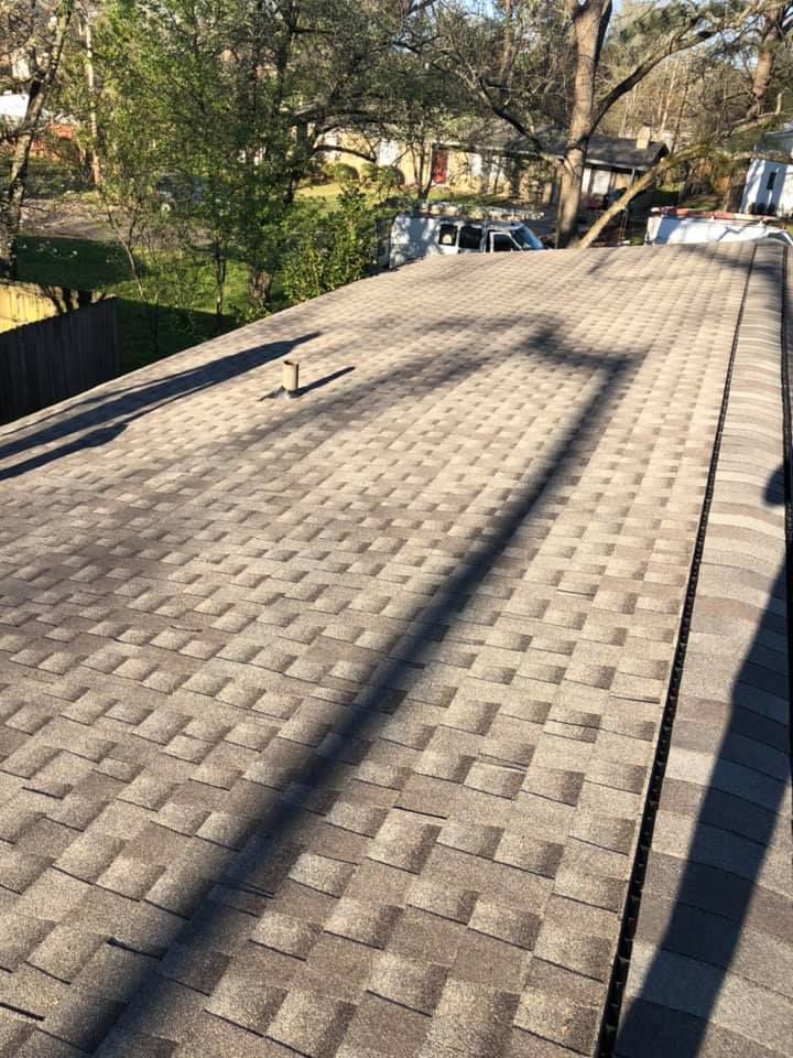 A shingle roof with dark streaks from a nearby power line.